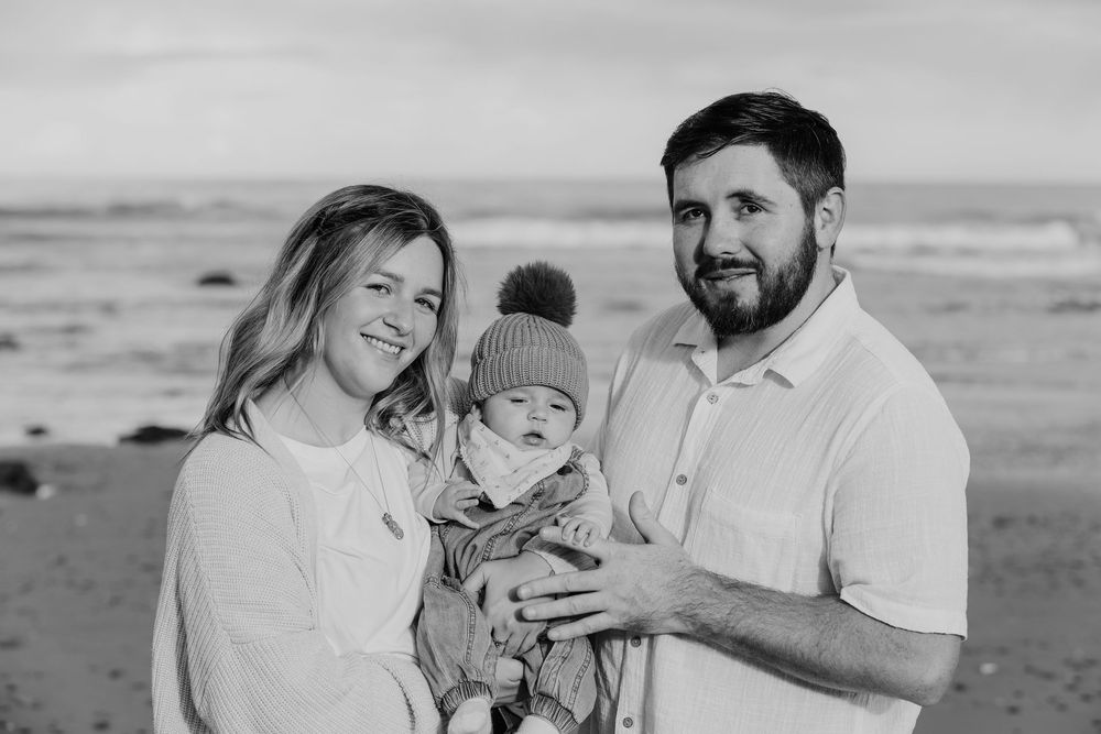 Family portraits captured on scenic beach with rocky cliffs.