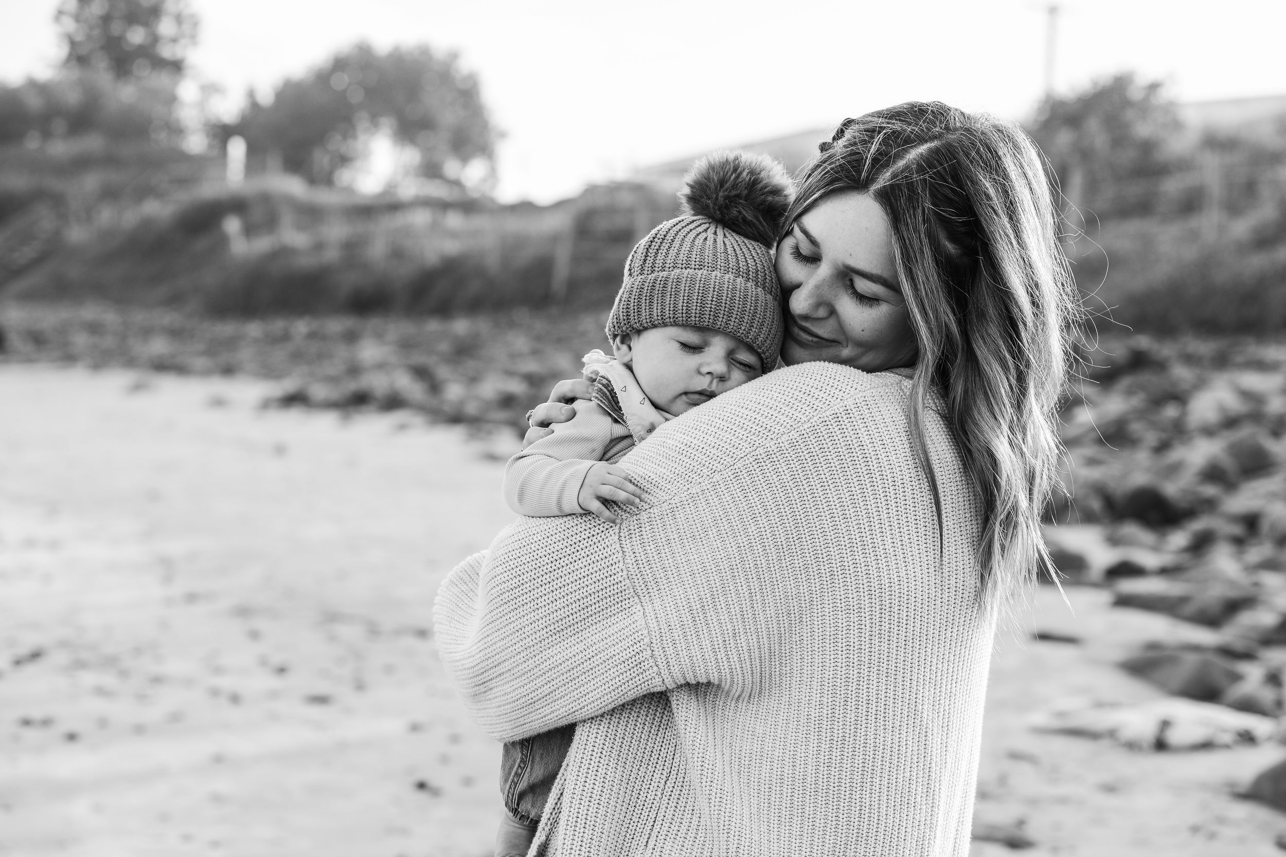 A touching moment between parent and child sharing an embrace at a beach in muted tones.