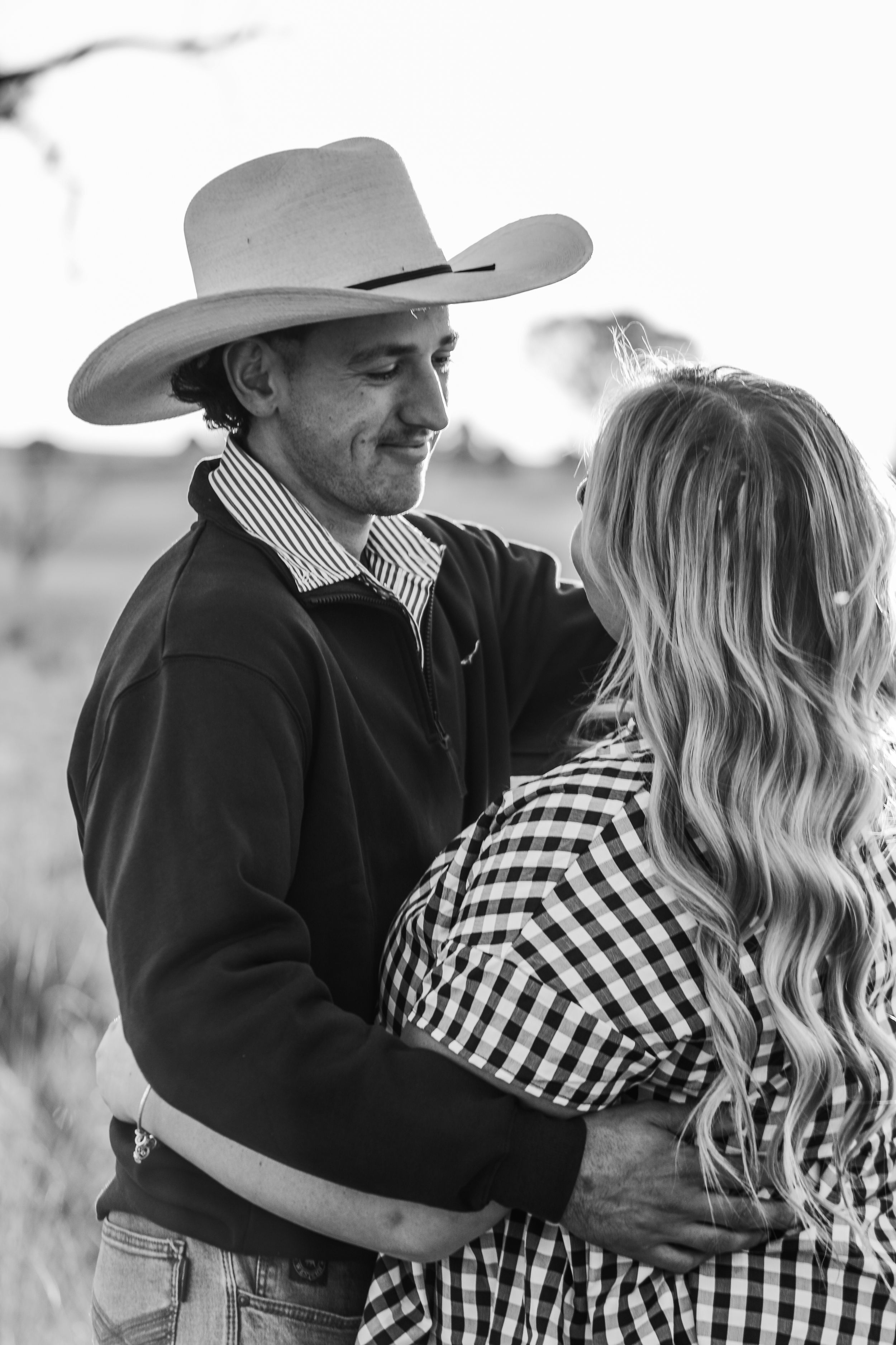 Black and white portrait of couple in western wear sharing intimate moment.