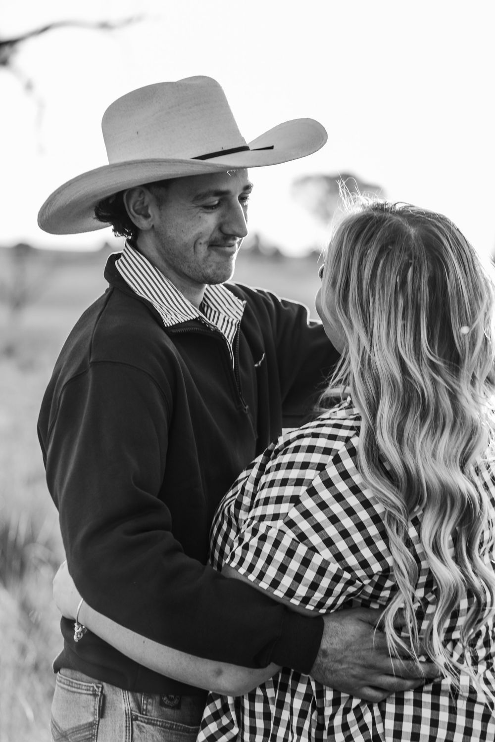 Black and white portrait of couple in western wear sharing intimate moment.