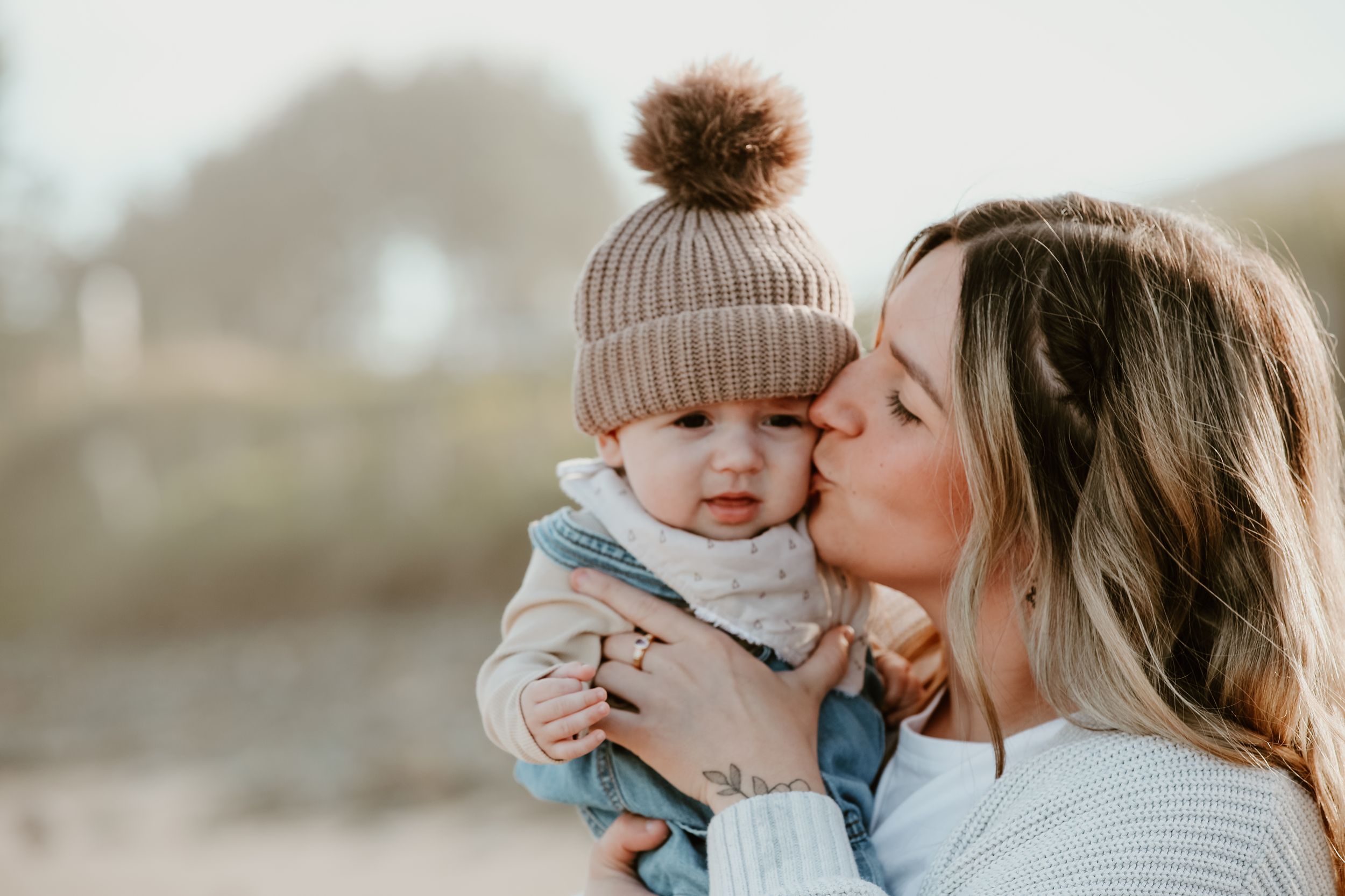 Sweet candid moments of affection captured between parent and baby in black and white photography.