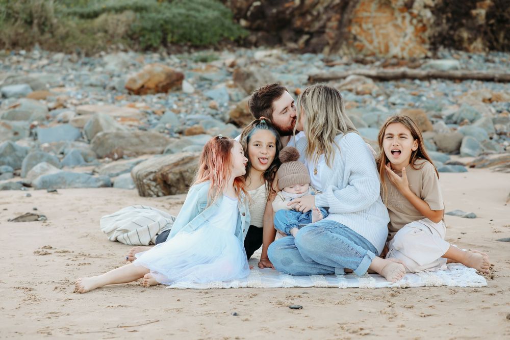 Relaxed family portrait session on a beach with everyone dressed in light colors.