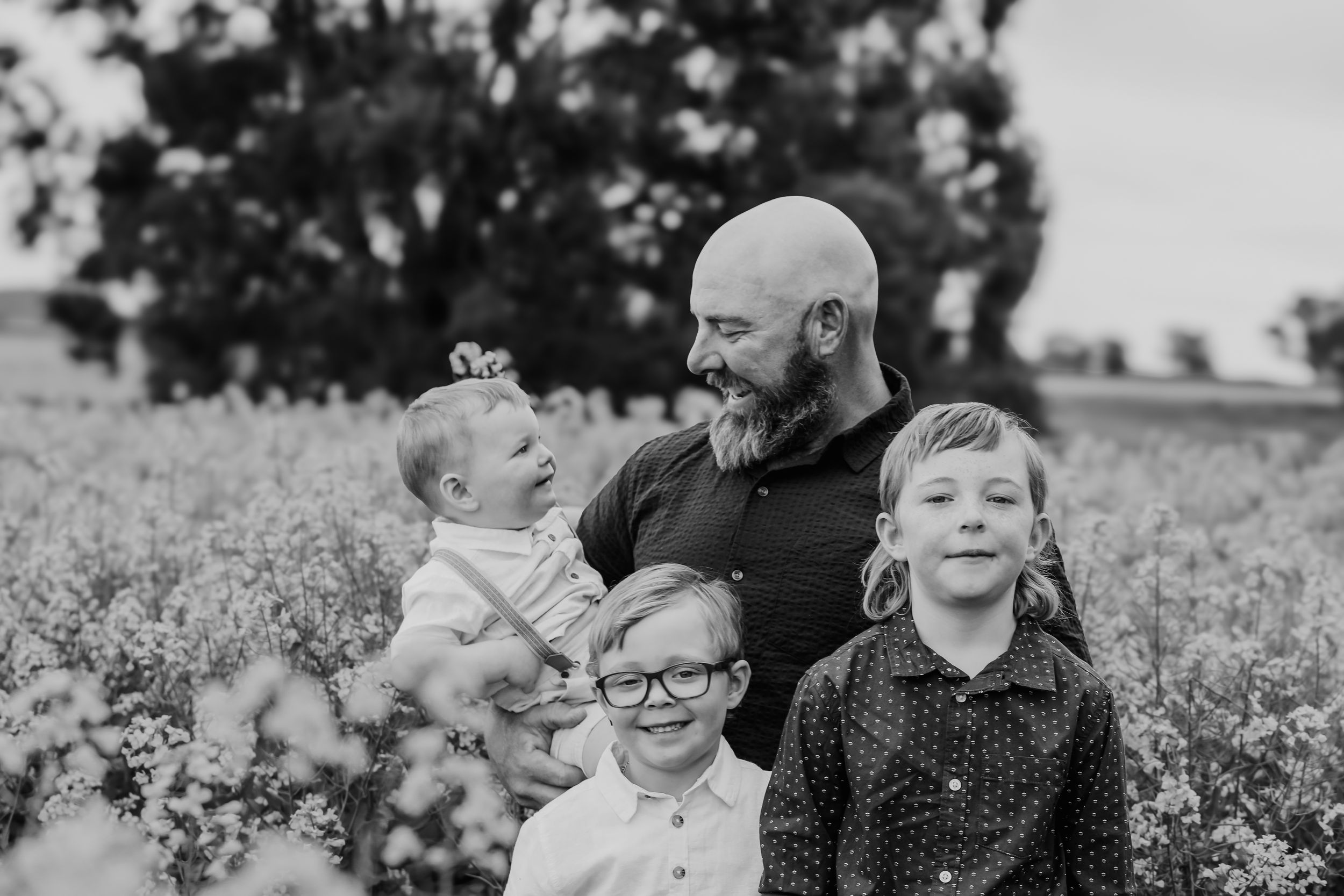 Joyful family moments captured in black and white photography among blooming flowers.