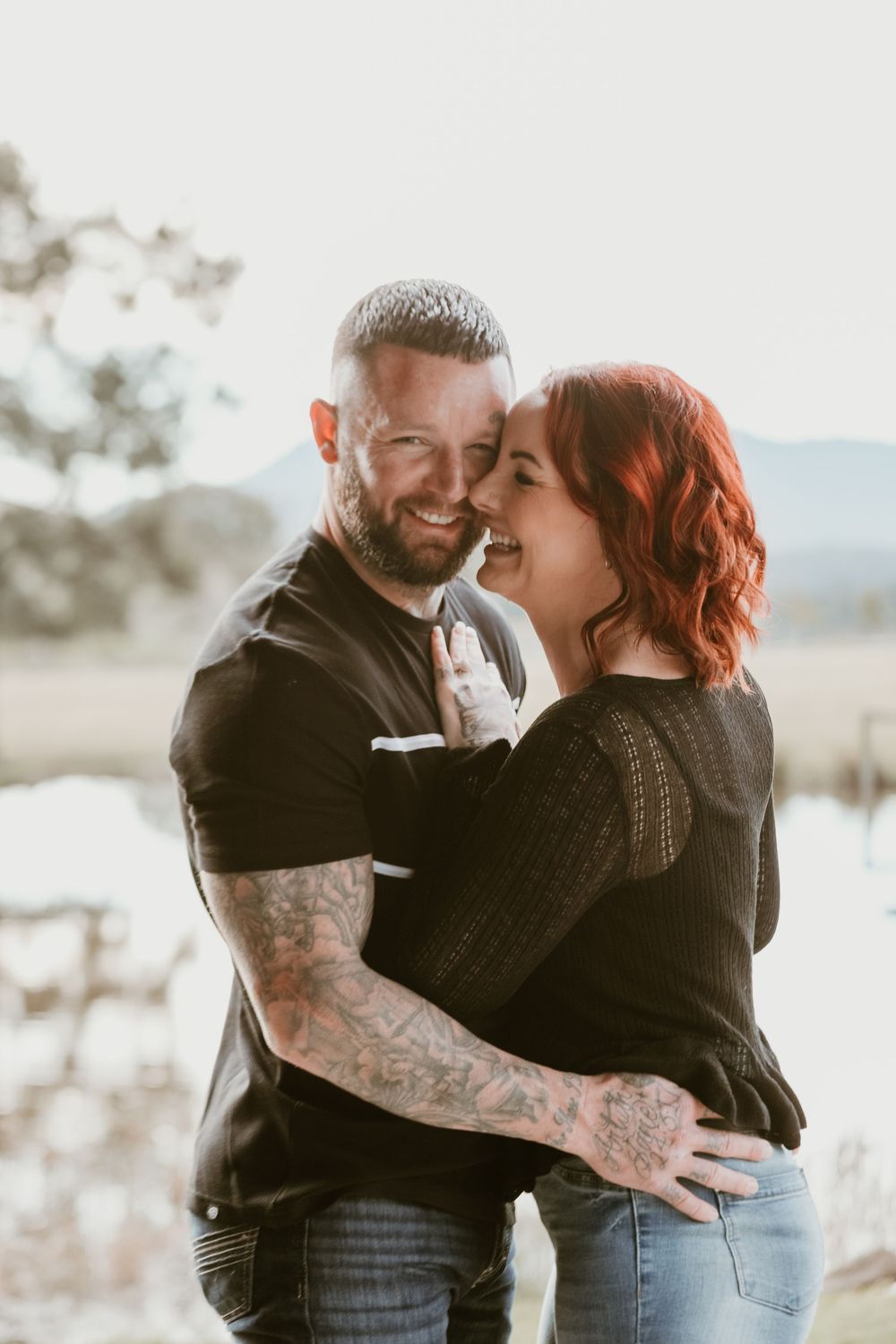 Couple embracing and laughing together in soft sunset light.