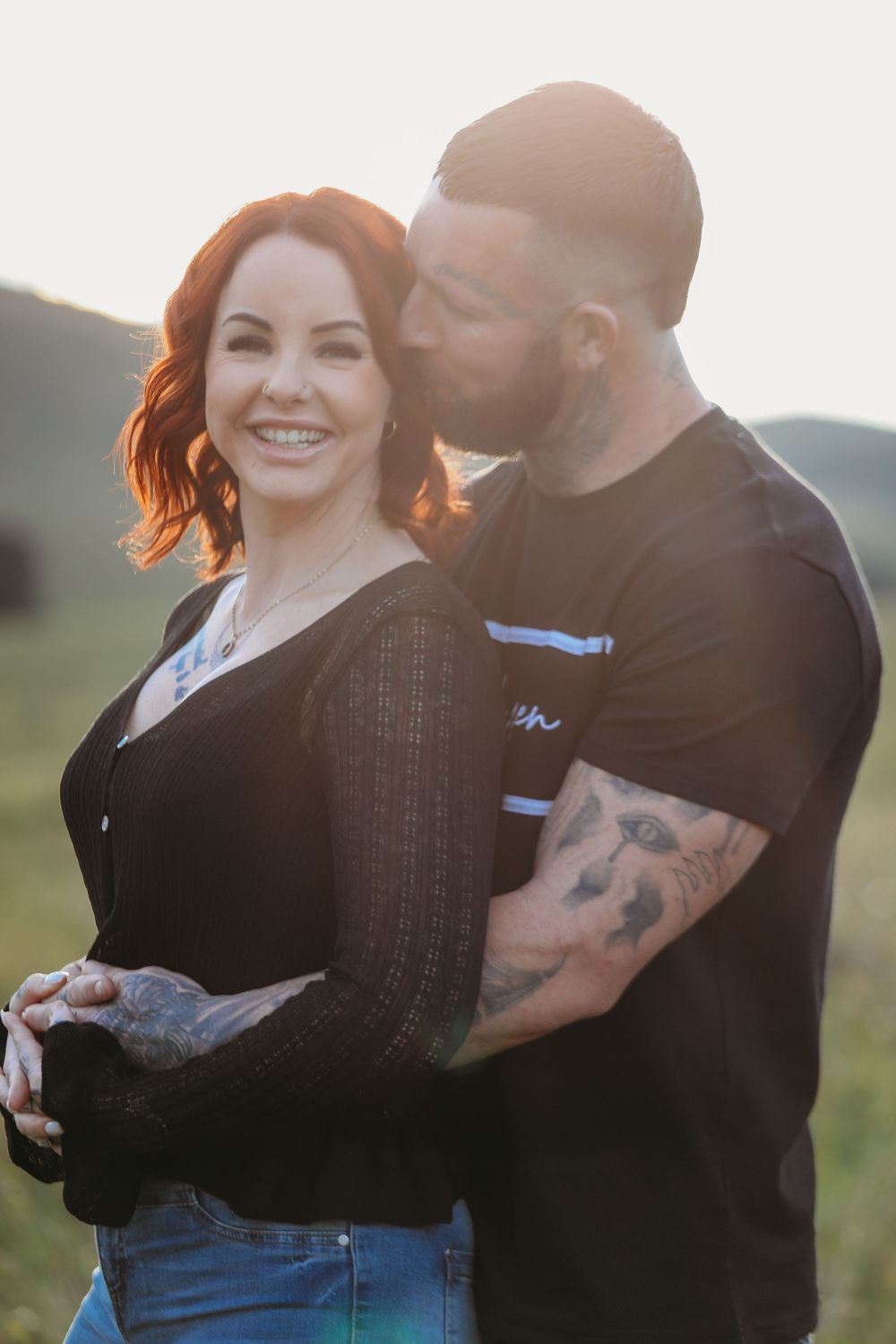 Couple in casual clothing embracing outdoors during sunset.