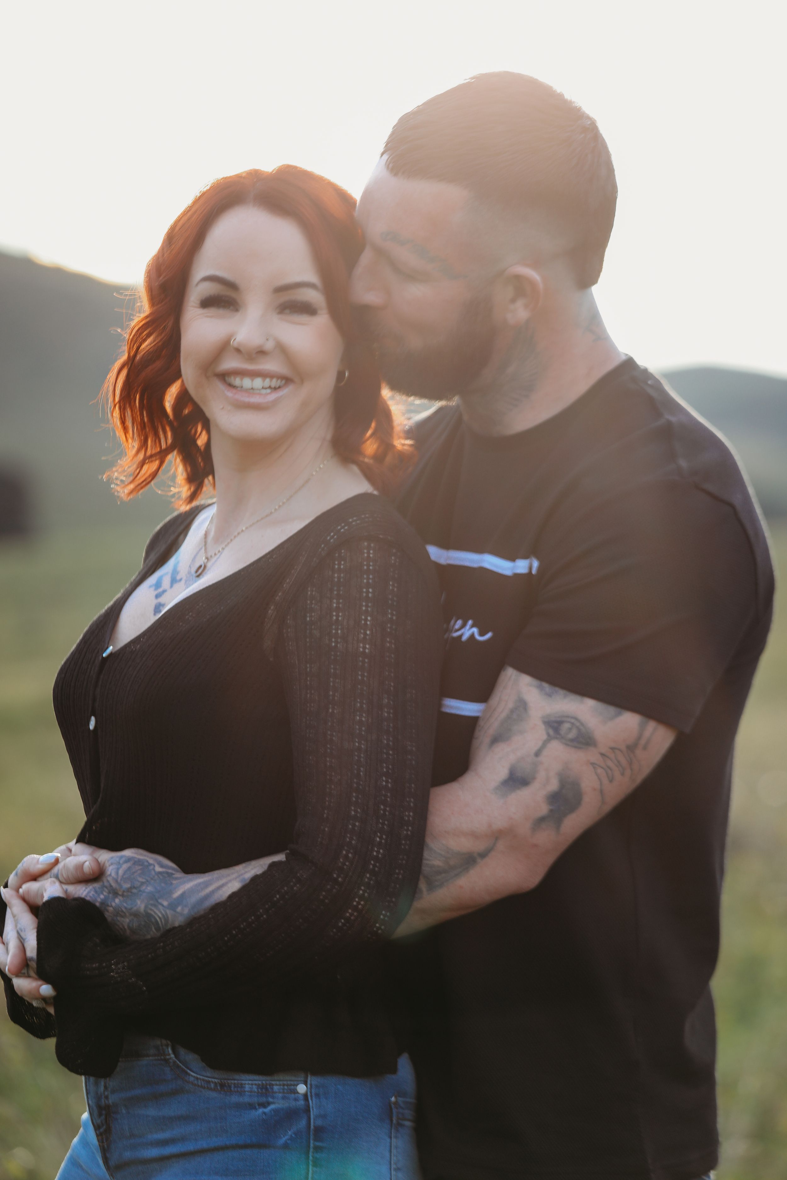 Couple in casual clothing embracing outdoors during sunset.