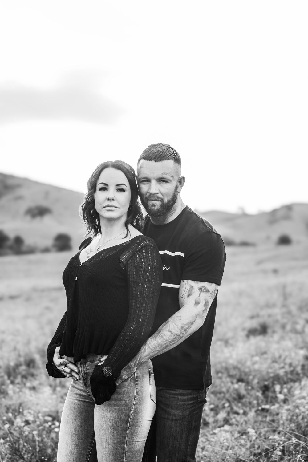 Black and white portrait of couple standing together in an outdoor field.