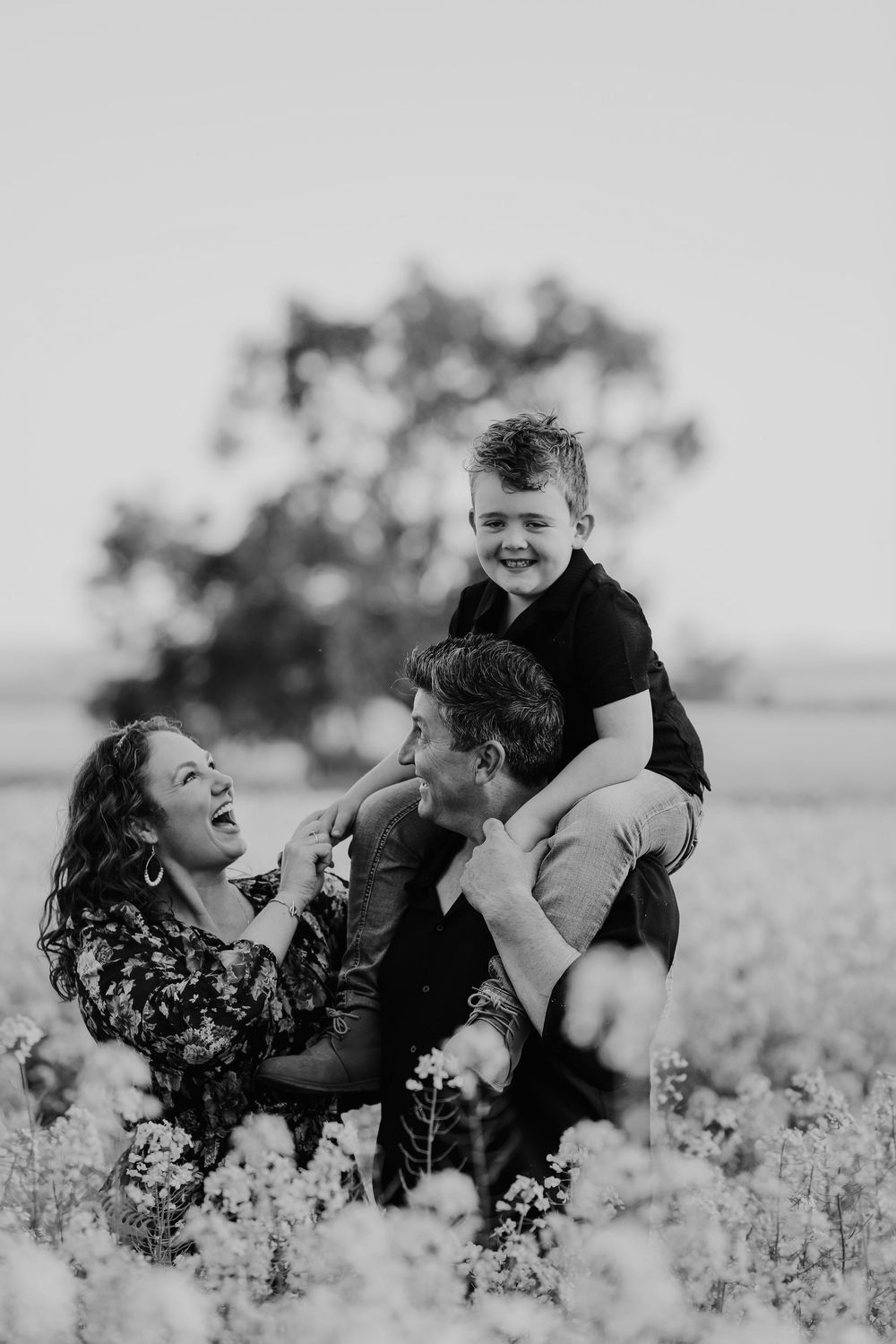 Candid black and white family portrait in a flowering meadow.