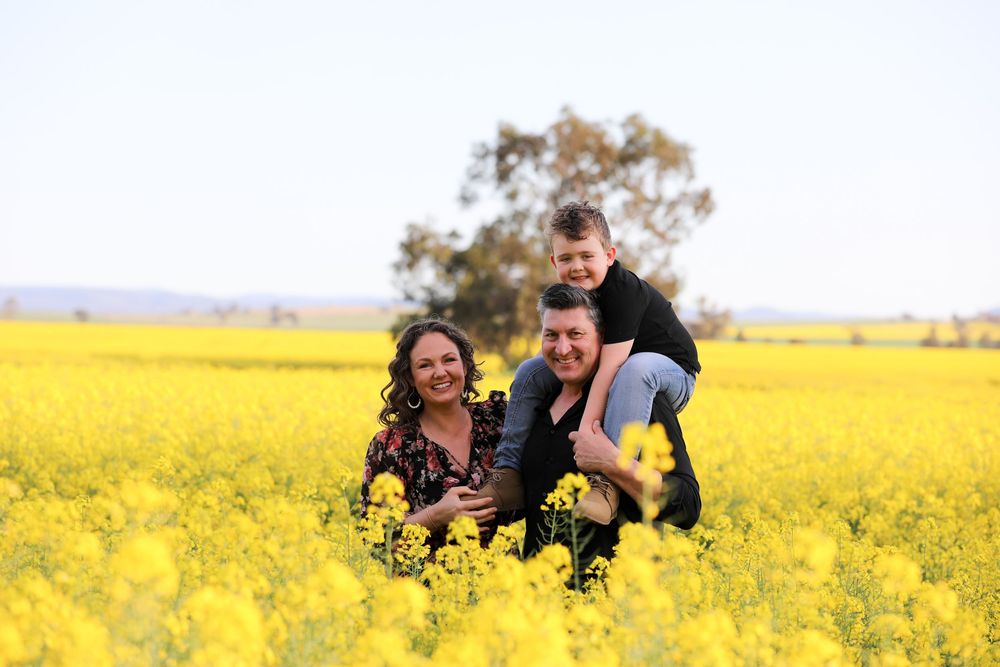 Family playing together in a vibrant yellow canola field on a sunny day.