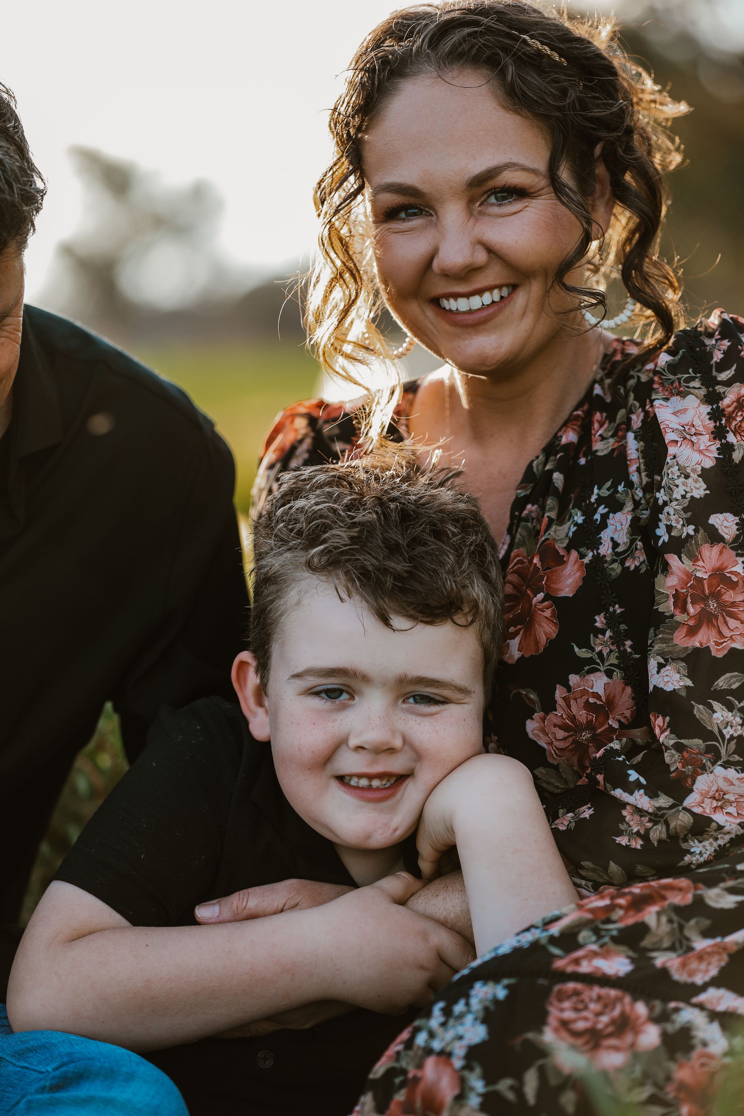 Family enjoying playful candid moments together in flowering field.