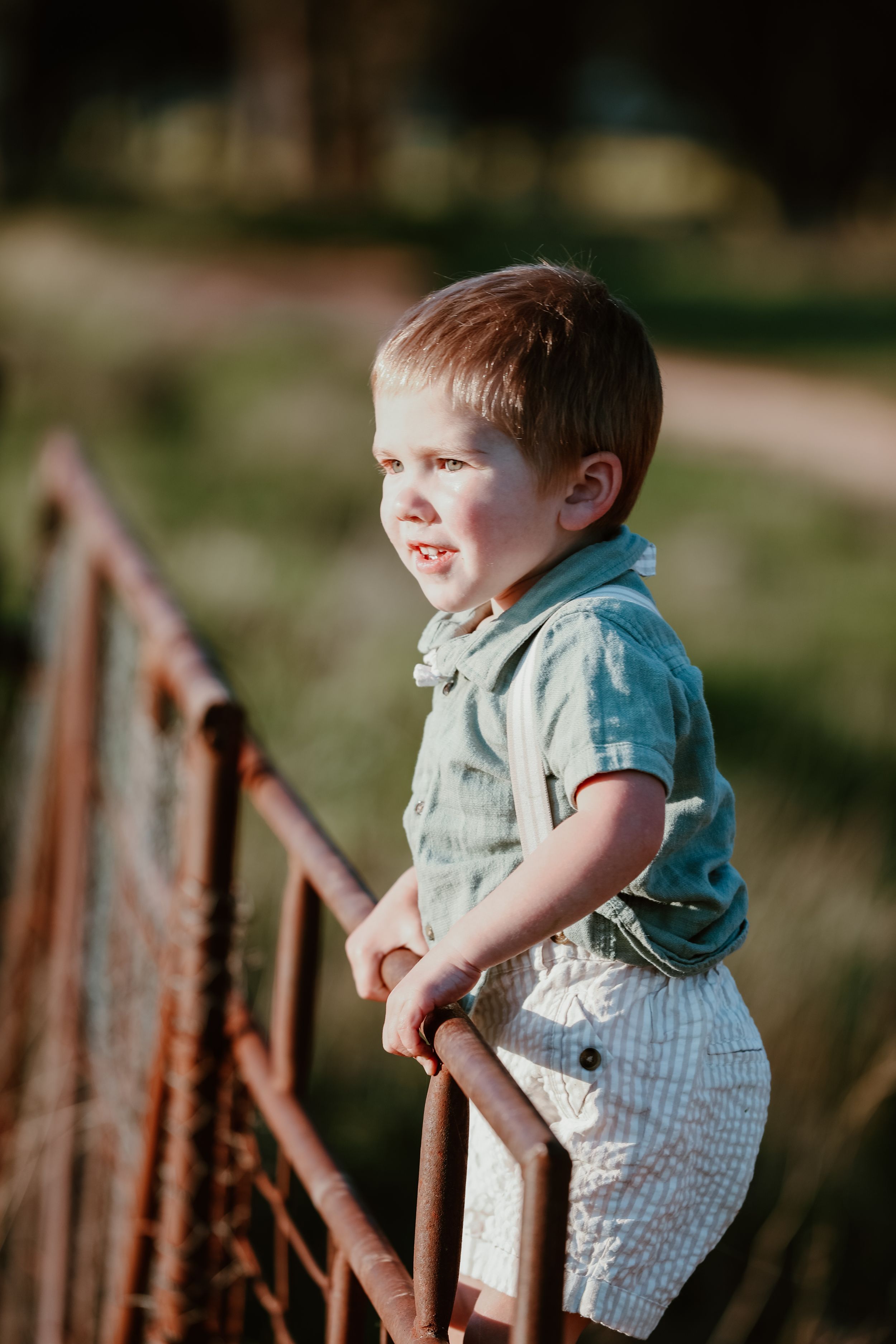 Child playing near rustic wooden fence in afternoon sunlight.