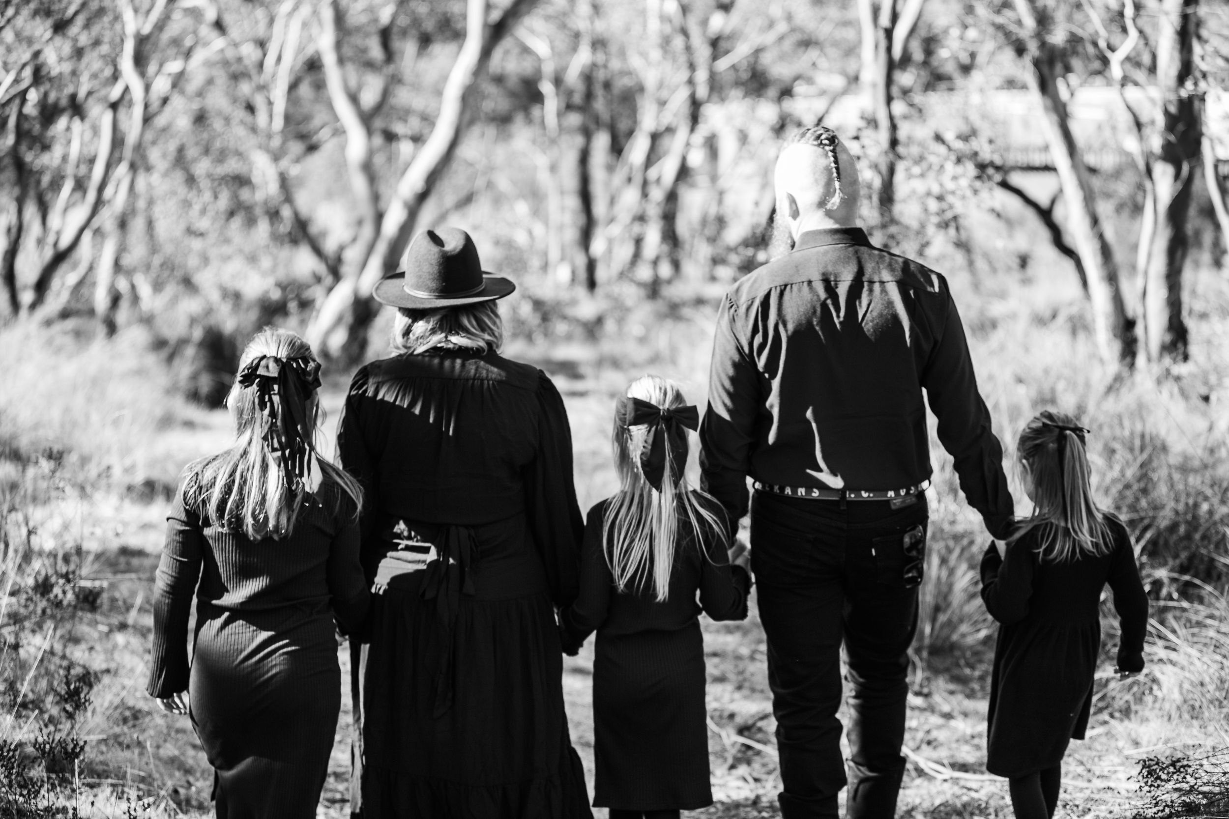 People dressed in black walking together through a rustic outdoor setting.