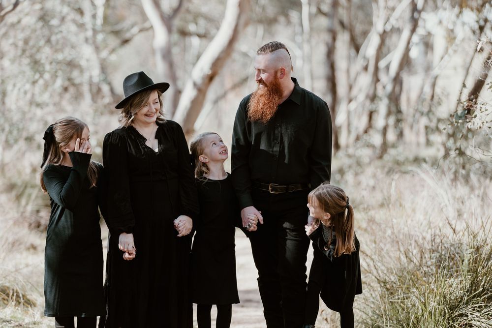 Group walking together through a wooded area wearing coordinated black outfits.