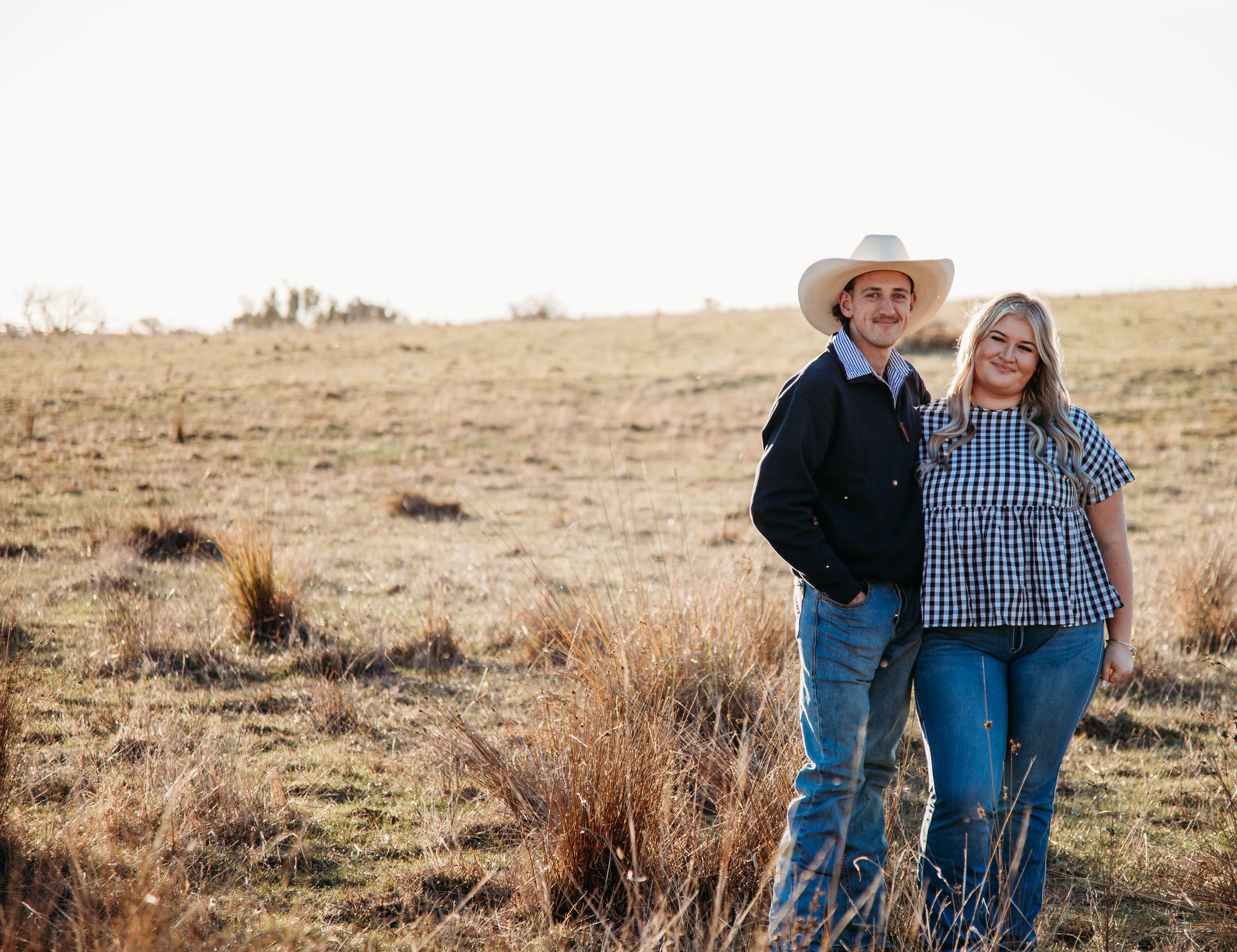 Family sharing a tender moment in a golden field of canola flowers during sunset.