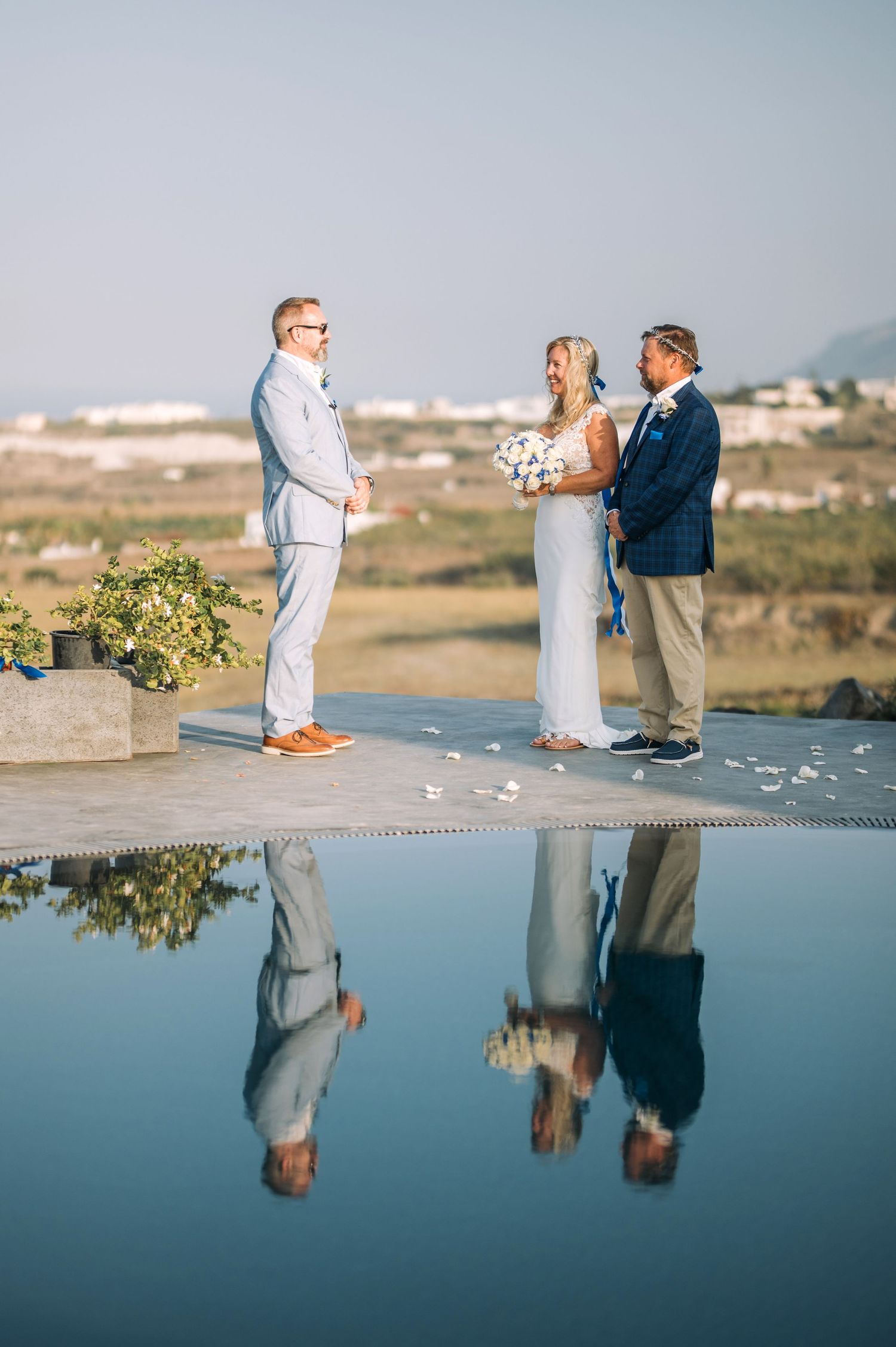 Outdoor wedding ceremony reflection in still water with mountains and sky in background.
