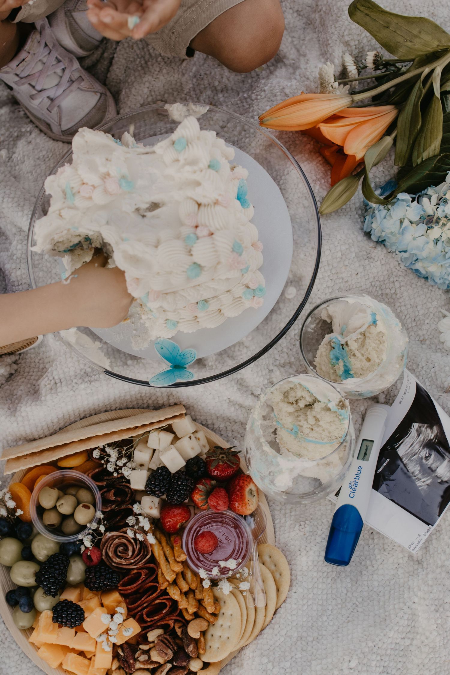 Overhead view of a party spread with cake, charcuterie board, and orange lilies.