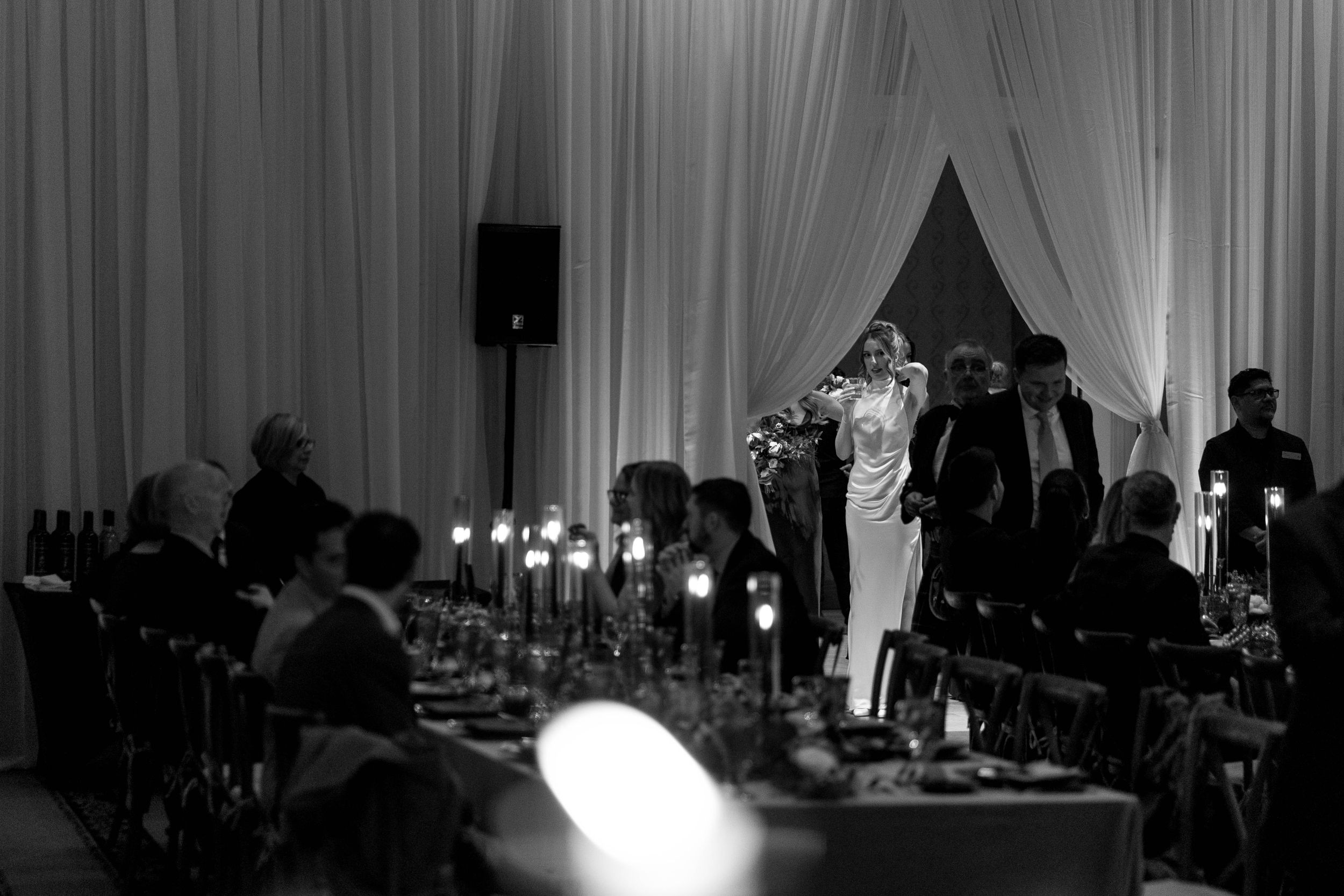 Elegant wedding reception setup with white draping and candlelit tables creating a romantic atmosphere.