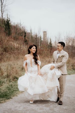 Couple walking together on path with bride's white dress flowing in the breeze.