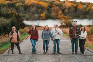 A group of people walking along a scenic path during autumn with colorful fall foliage in the background.