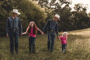 People wearing denim and casual attire walking together through a sunlit meadow at golden hour.