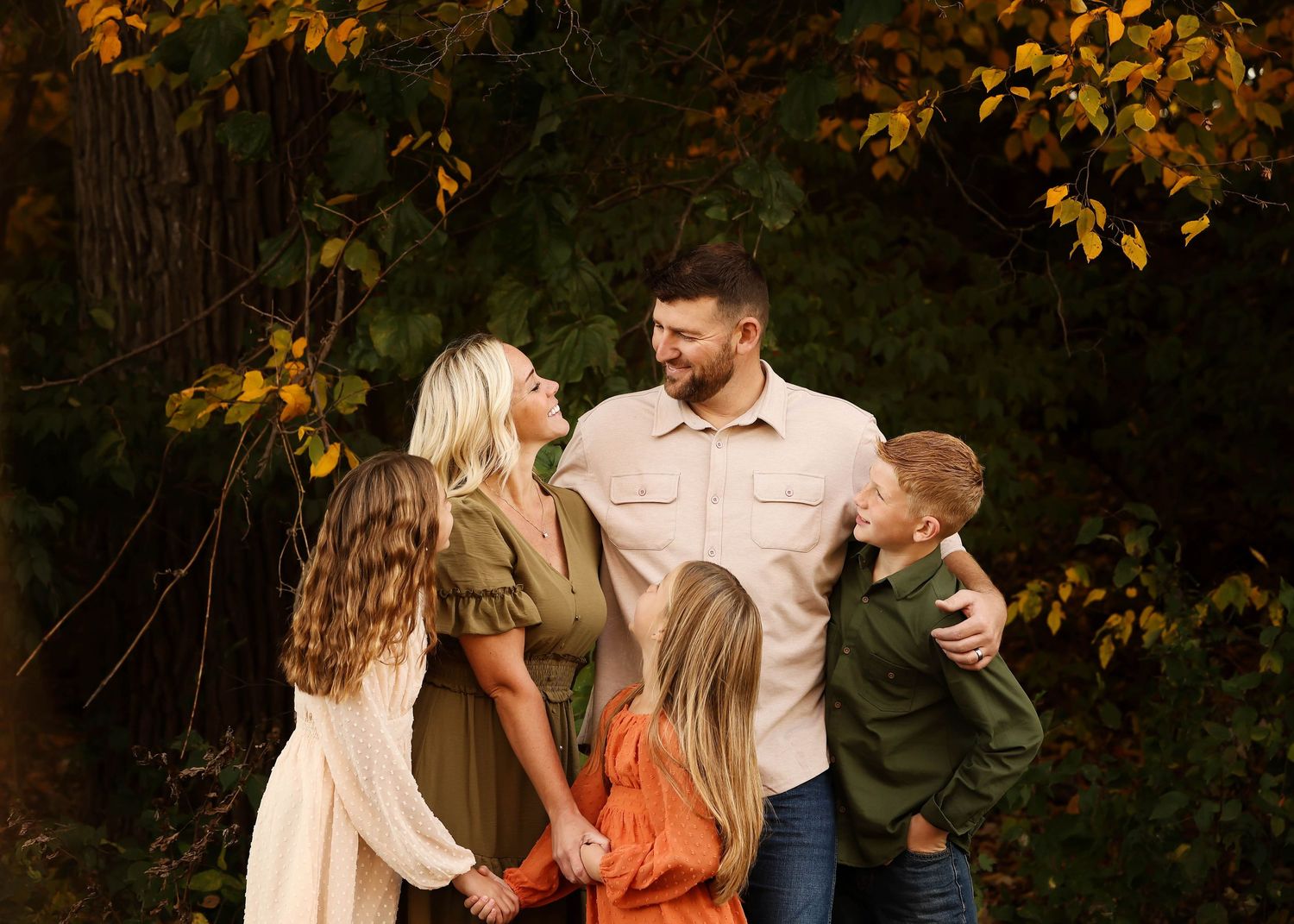 Casual autumn engagement photos with warm fall foliage in the background.