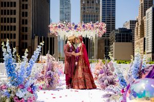 Ornate wedding ceremony setup with floral arch and colorful decorations against urban cityscape backdrop in downtown setting.