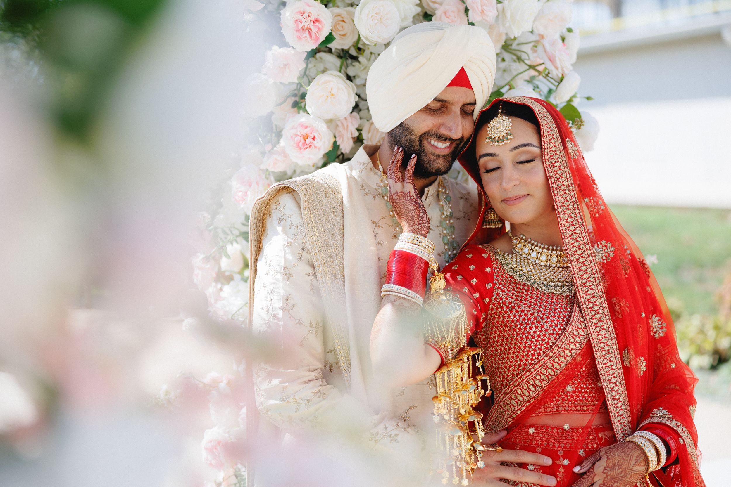 A couple in traditional Indian wedding attire share intimate moments during their celebration ceremony.