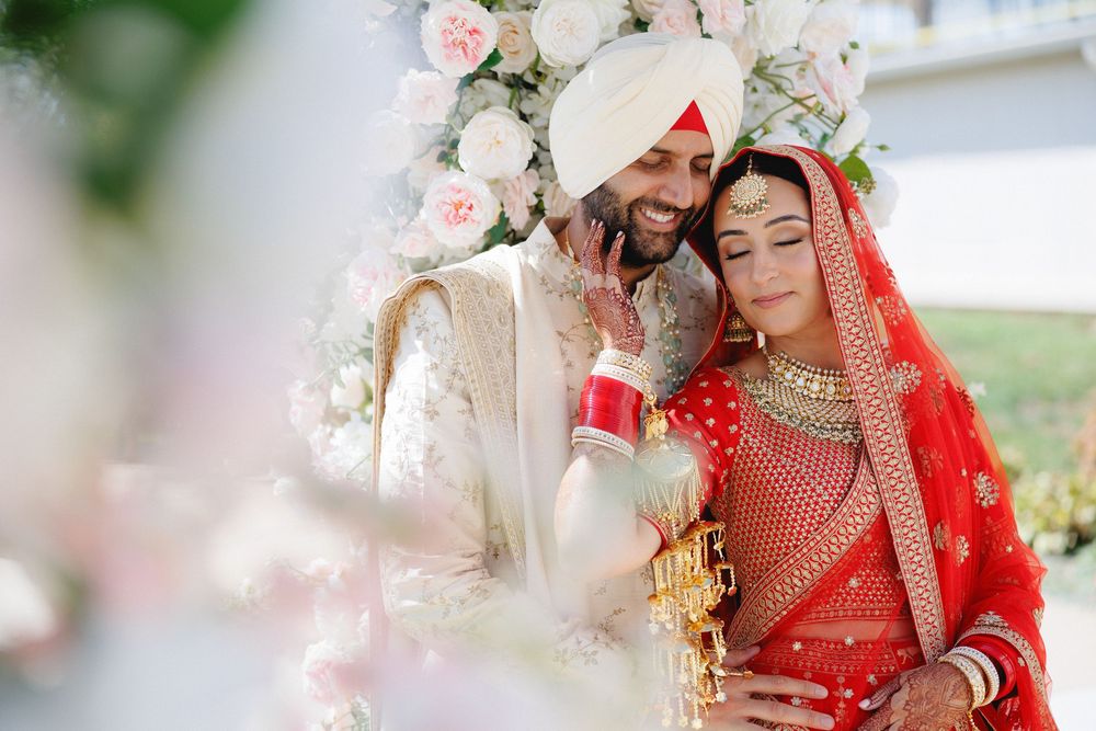 A couple in traditional Indian wedding attire share intimate moments during their celebration ceremony.