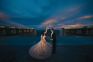 Dramatic sunset wedding portrait on a waterfront deck with dark moody sky.