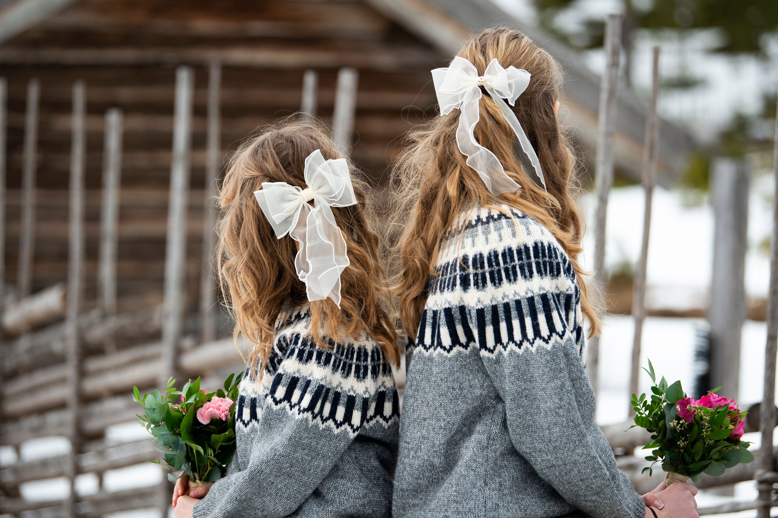 A woman in a cozy gray sweater and striped scarf holds a Christmas wreath outdoors in the winter.