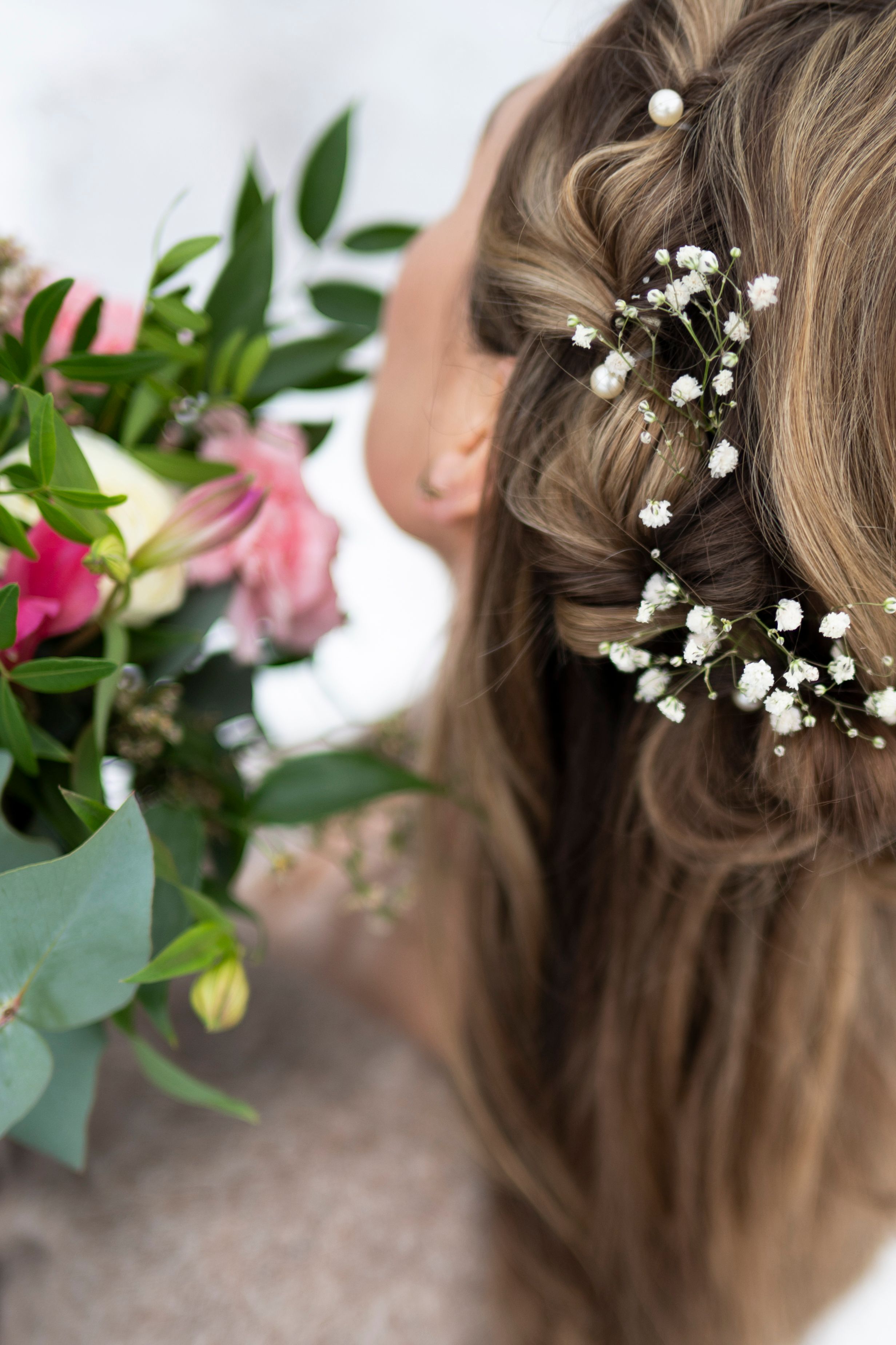 Delicate white baby's breath flowers woven into braided brown hair with floral decorative accents.