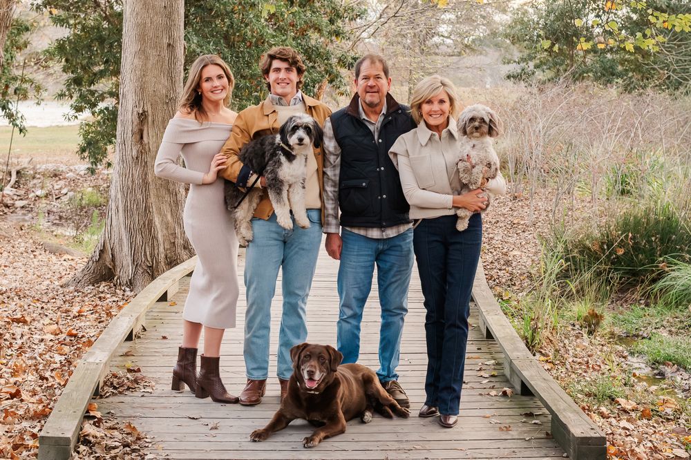 Family of four and three dogs posing on a wooden bridge at Trilith, Fayetteville, GA