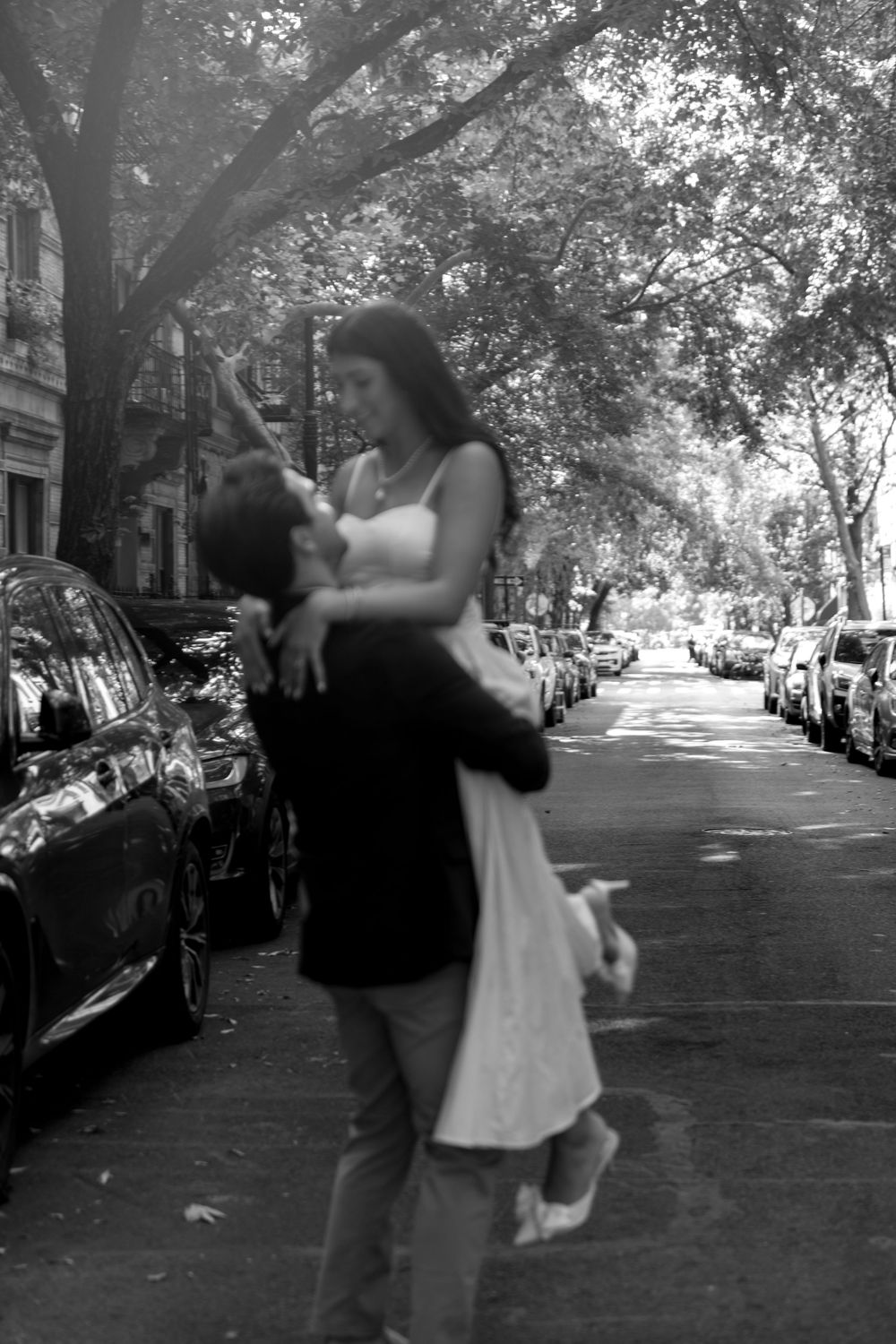 A playful dance sequence on a leafy urban street with cars parked along the curb.