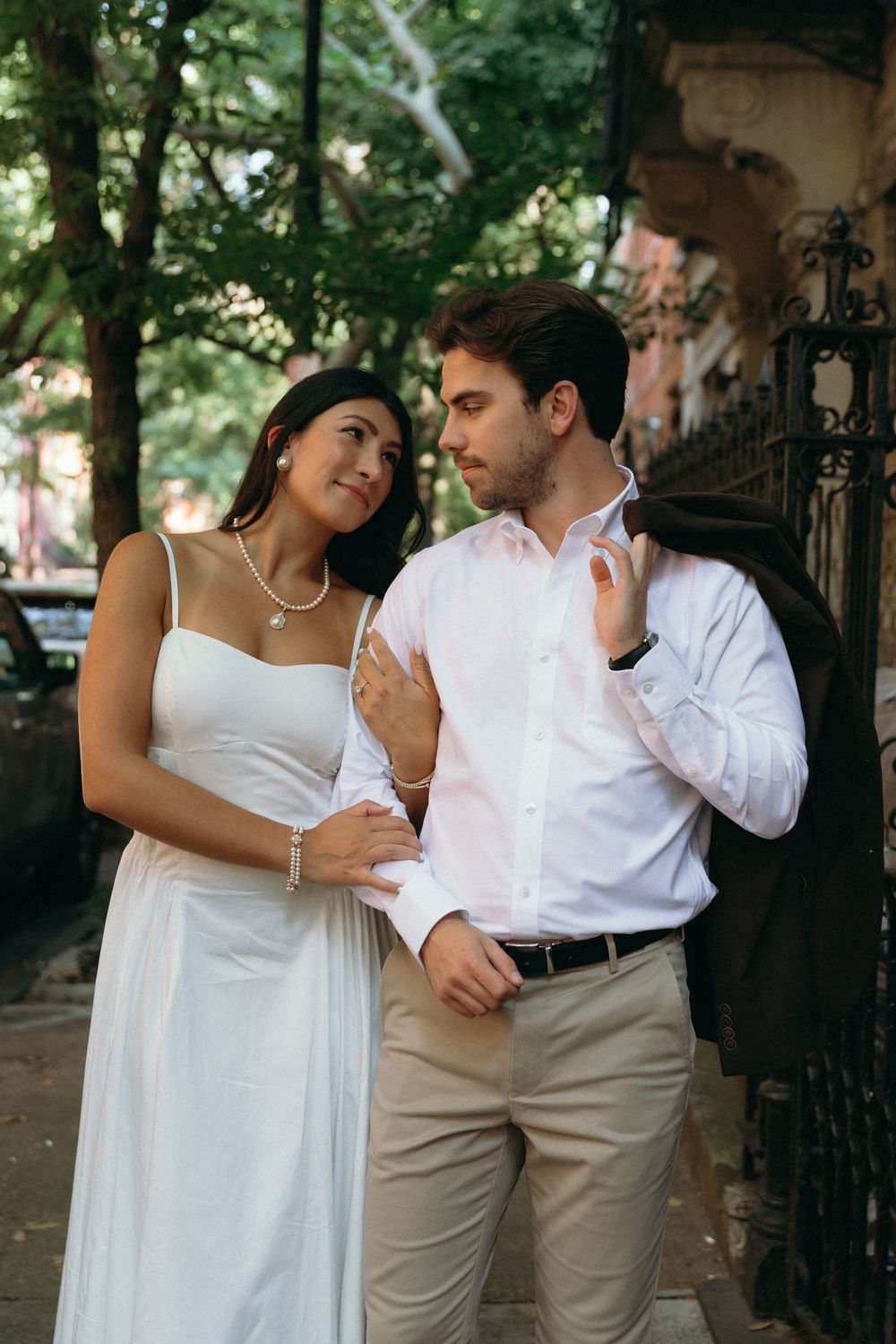 A romantic couple in white and khaki poses together on a brownstone stoop.