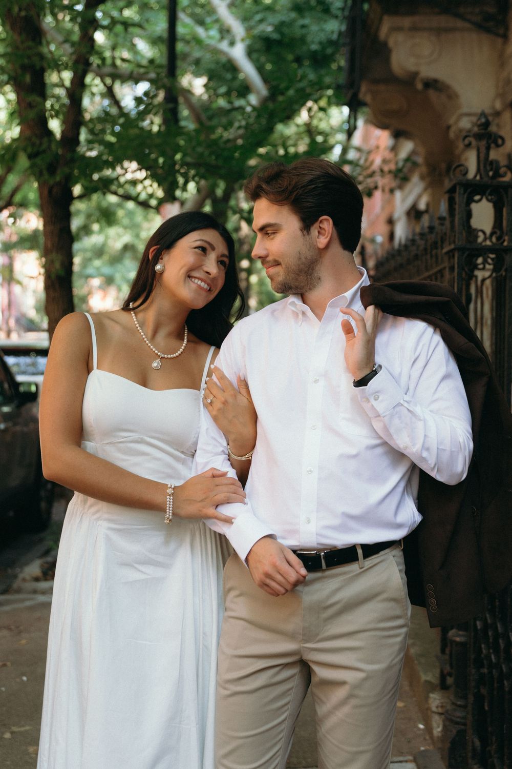 A couple shares an intimate moment while posing on a shaded city street.