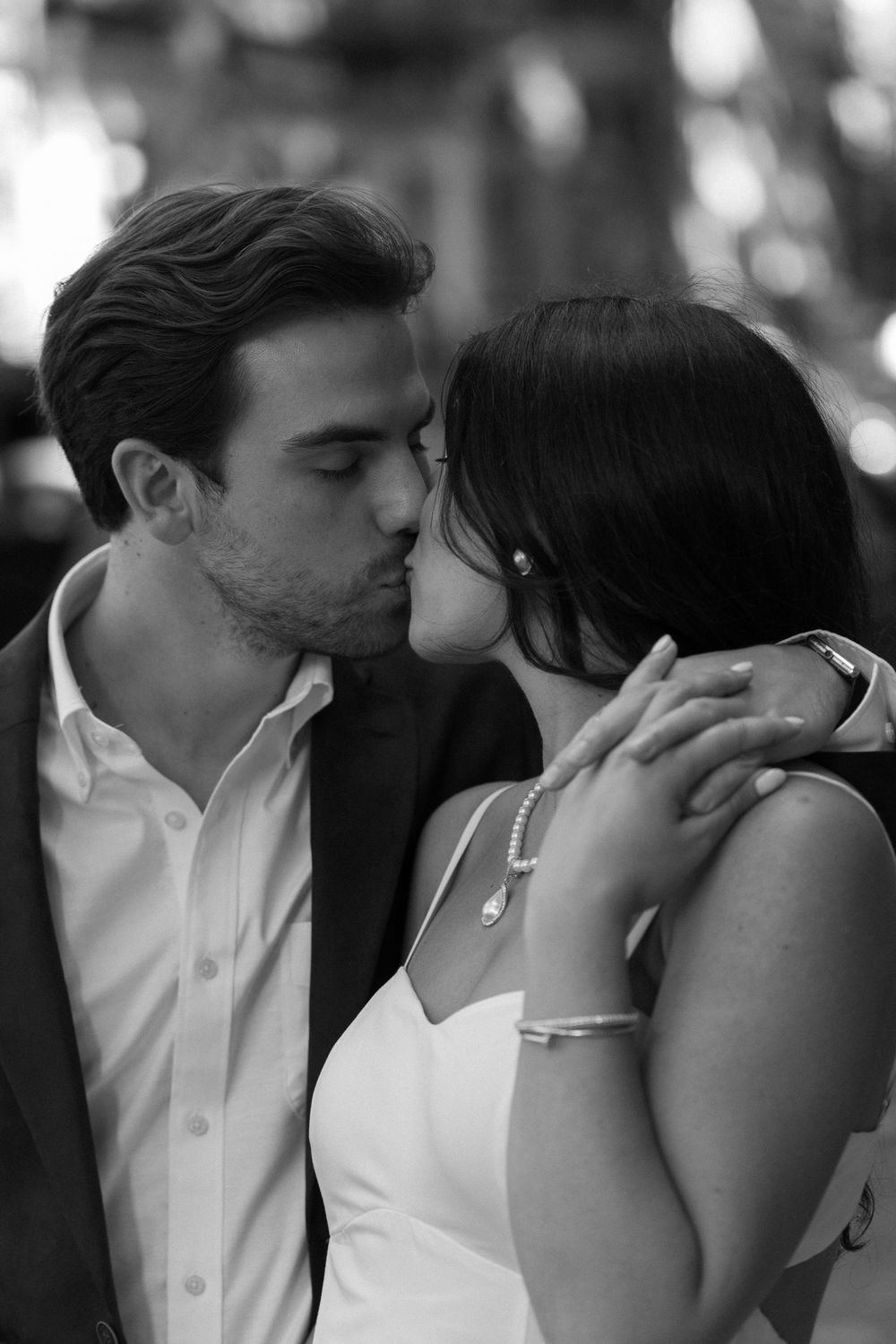 Intimate black and white portrait of a couple sharing a tender kiss while dressed in formal attire.