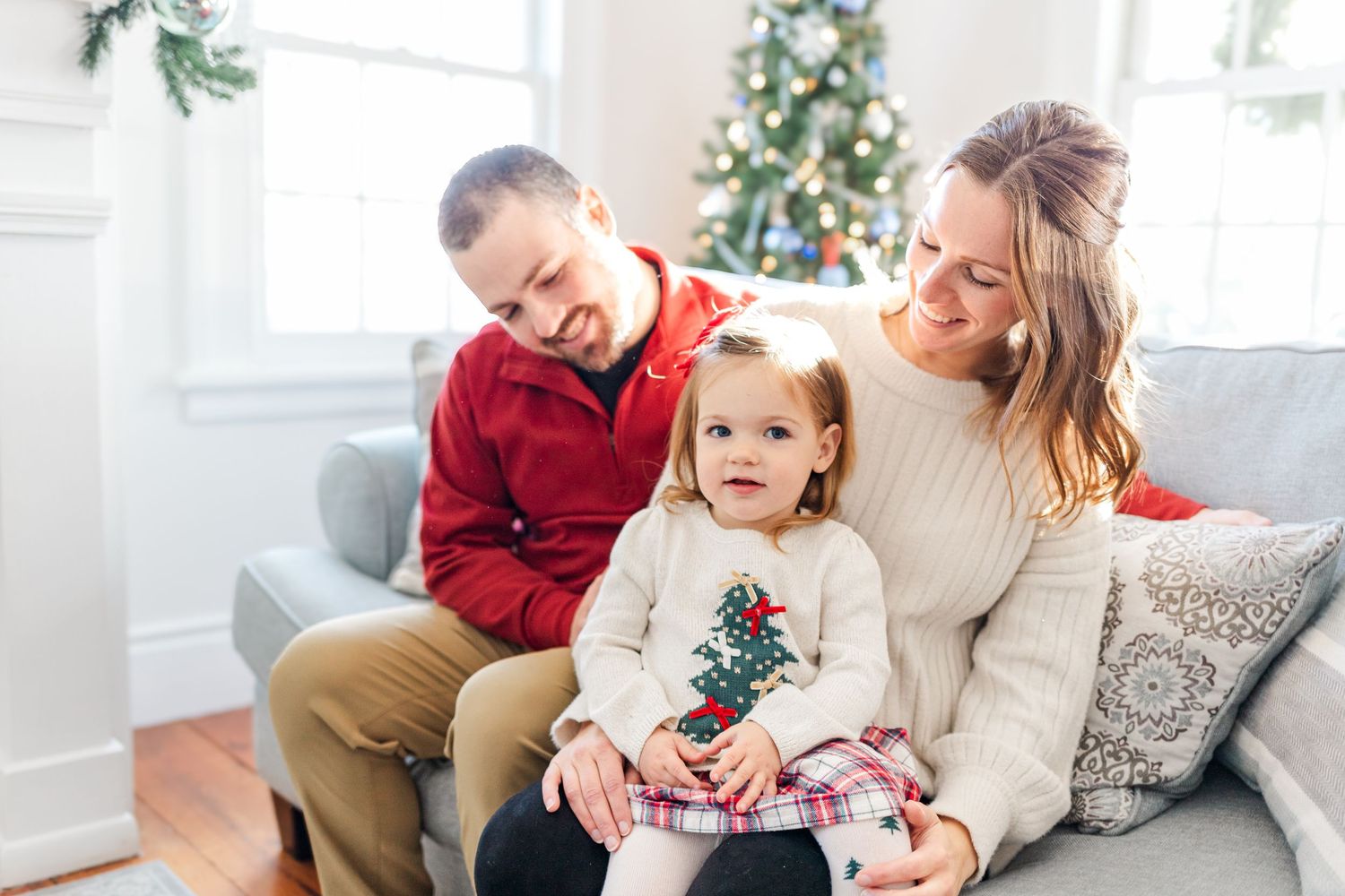 Family smiling on a couch during a light + airy Hudson Valley, NY Christmas Mini Session.