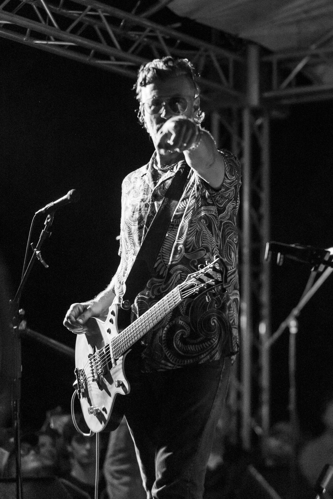 Black and white photo of musician playing bass guitar on stage.