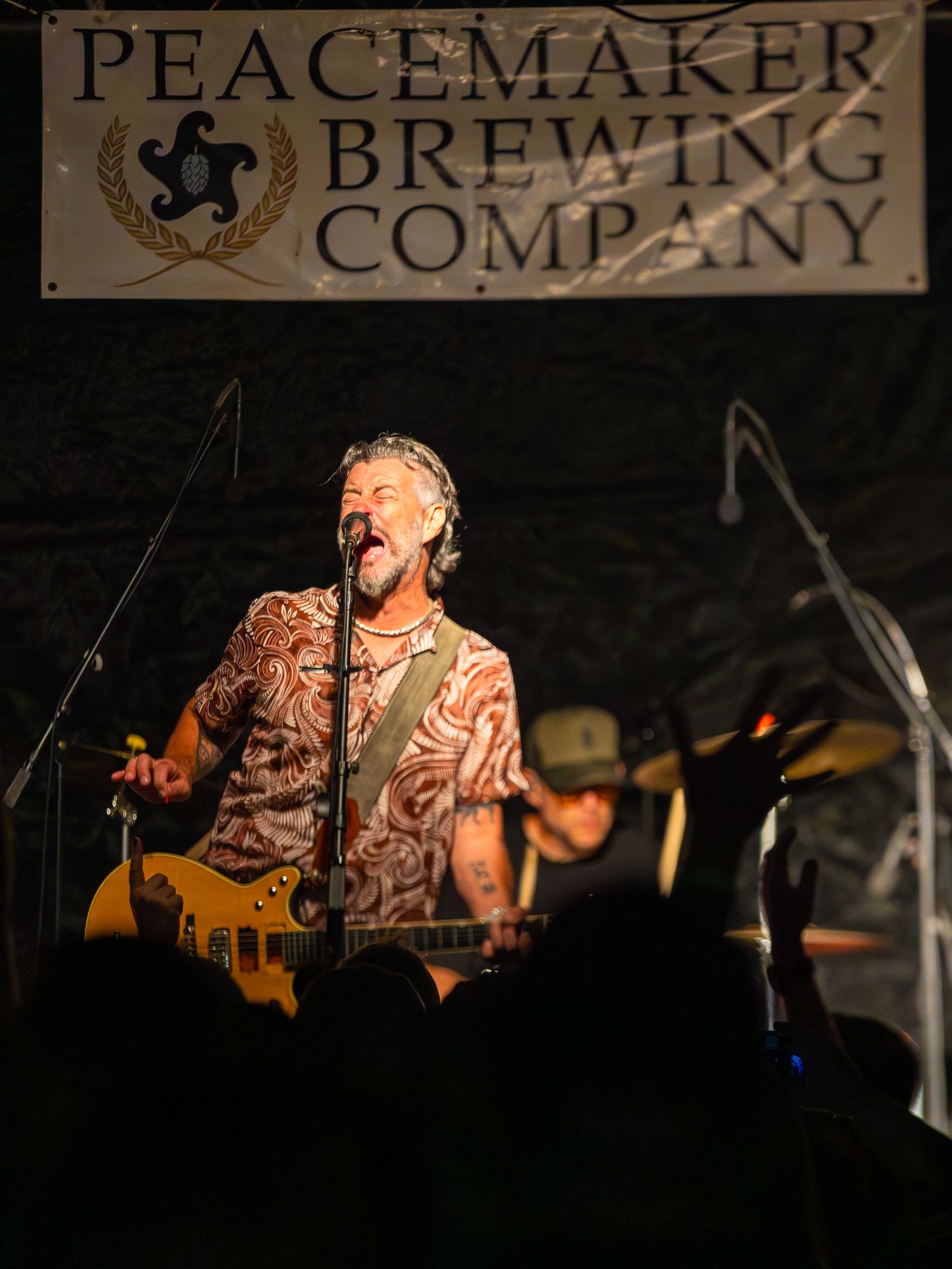 Performer singing passionately on stage at Peacemaker Brewing Company venue.