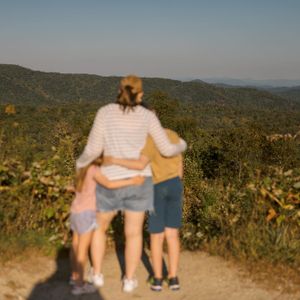 People sitting together on a scenic mountain overlook during sunset.