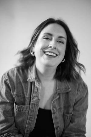 Candid black and white portrait showing joyful expression and casual denim style.