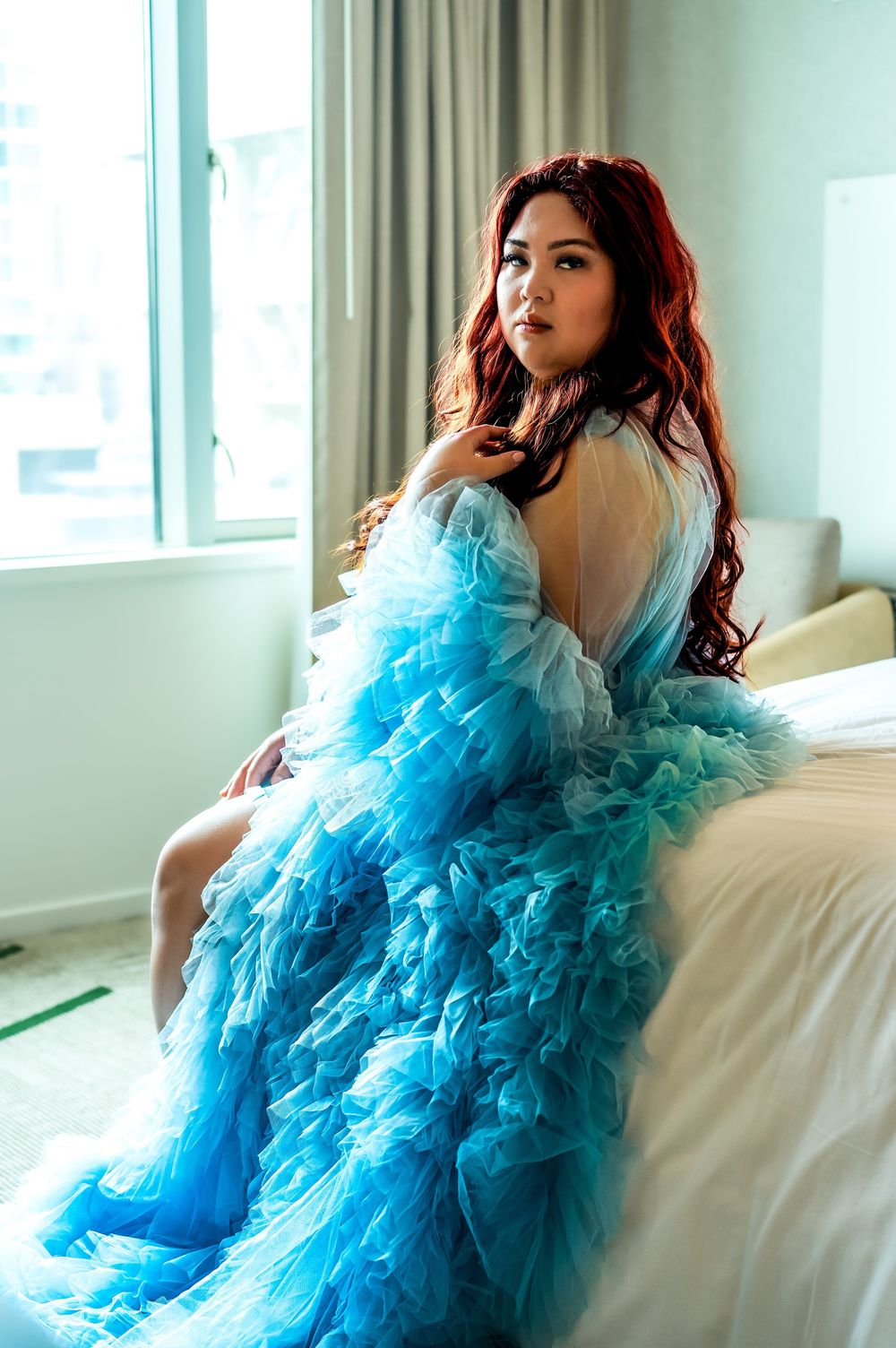 Elegant portrait session featuring dramatic turquoise tulle gown on white couch.