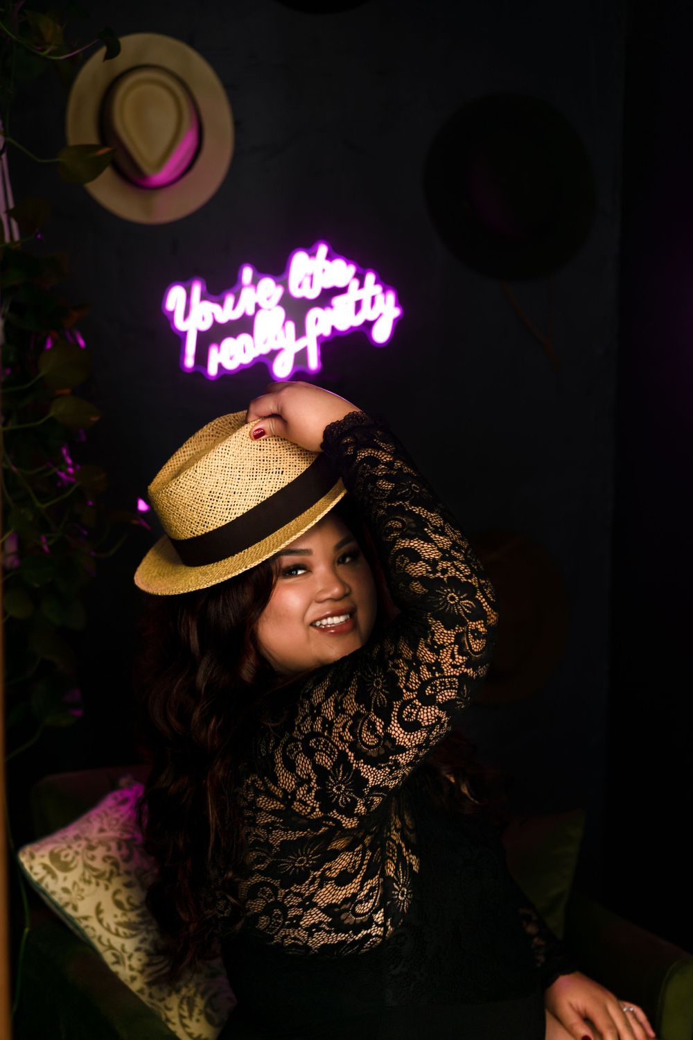Moody boudoir photography with straw hat and neon signs creating dramatic lighting effects.