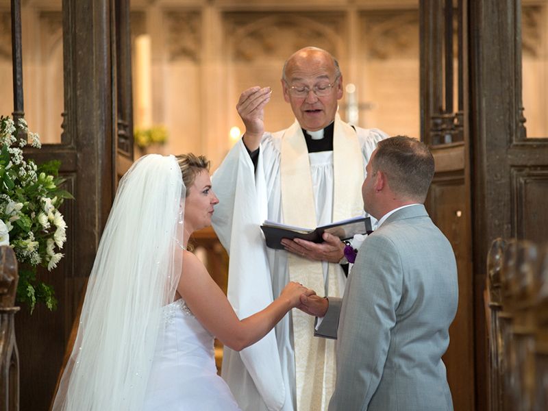 A couple photographed exchanging vows at St. Helen's Church in Benson, Oxfordshire, captured by Abigail's Studio.