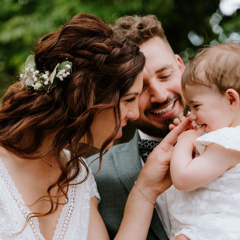 Brautpaar kuschelt mit kleinem Kind, inniger Familienmoment bei der Hochzeit, Hochzeitsreportage in Bayern.