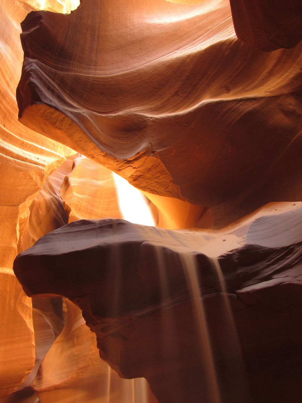 Warm orange light filtering through smooth curved sandstone walls of Antelope Canyon, Arizona.