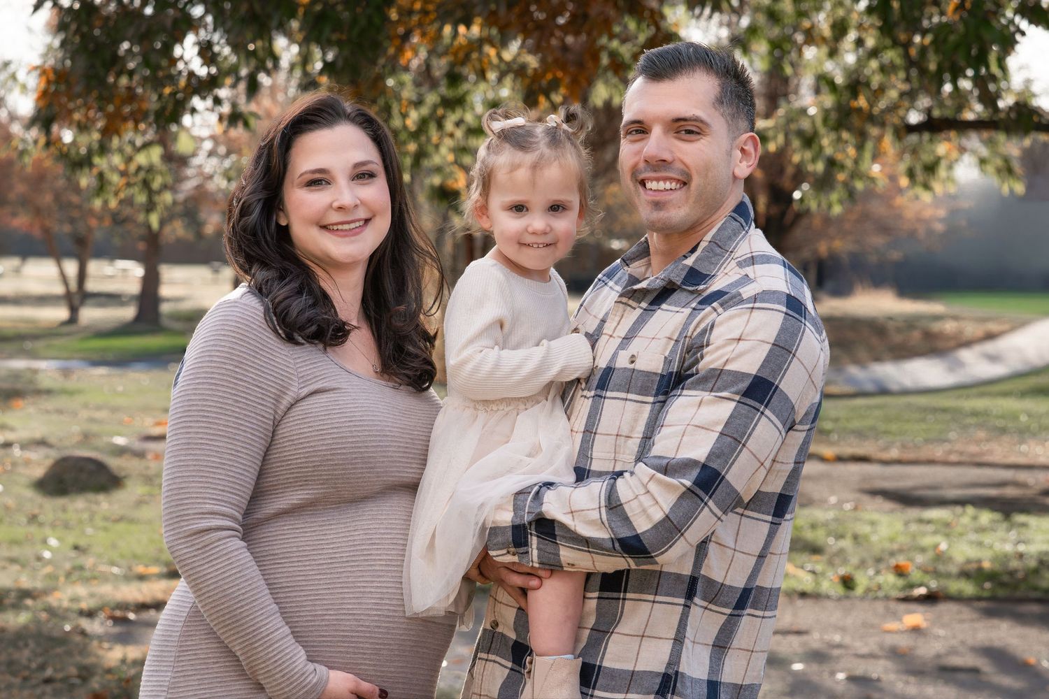 A family poses together outdoors in coordinating neutral outfits during a fall photo session.