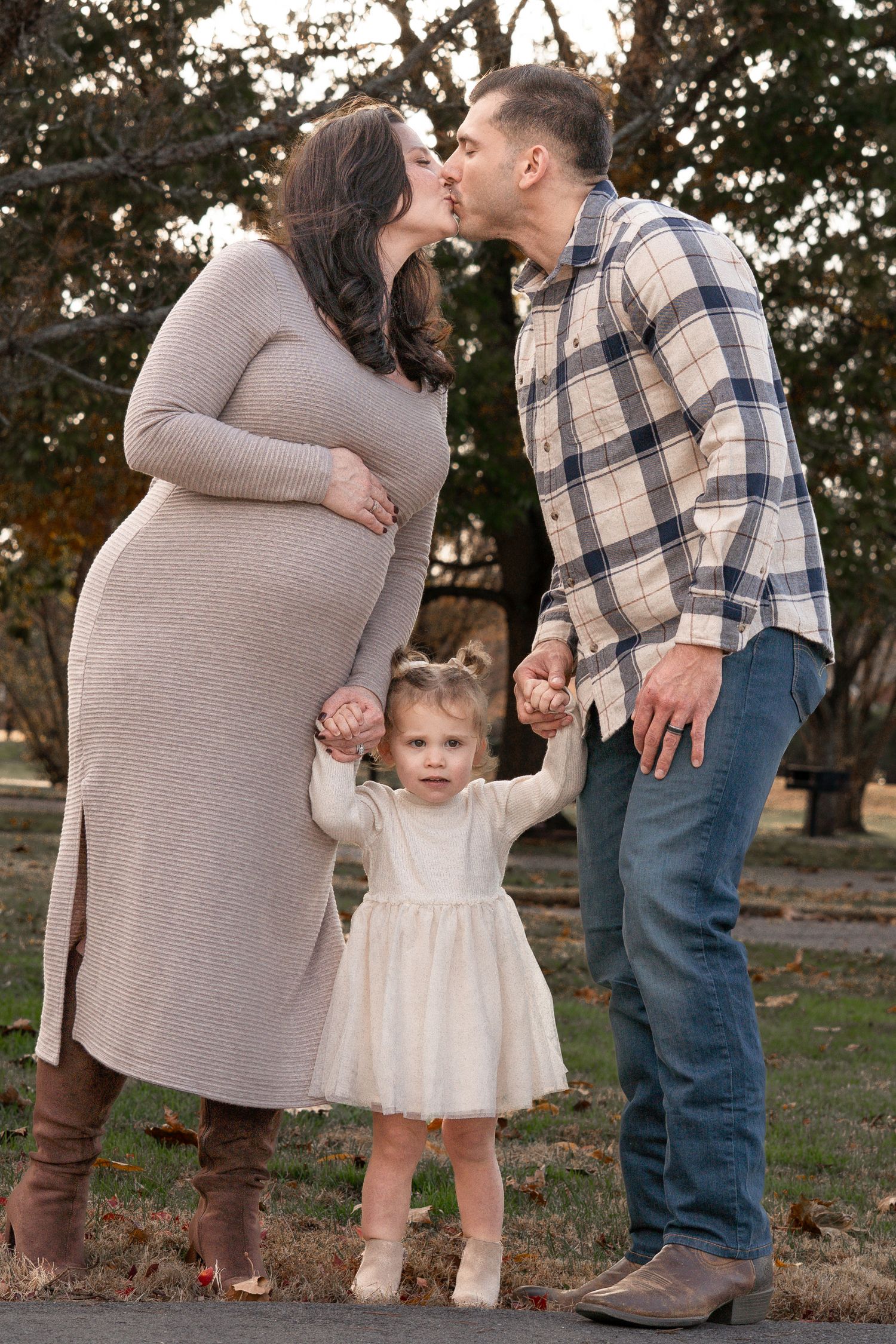 A sweet family moment captured in an outdoor autumn setting with warm lighting and fallen leaves.