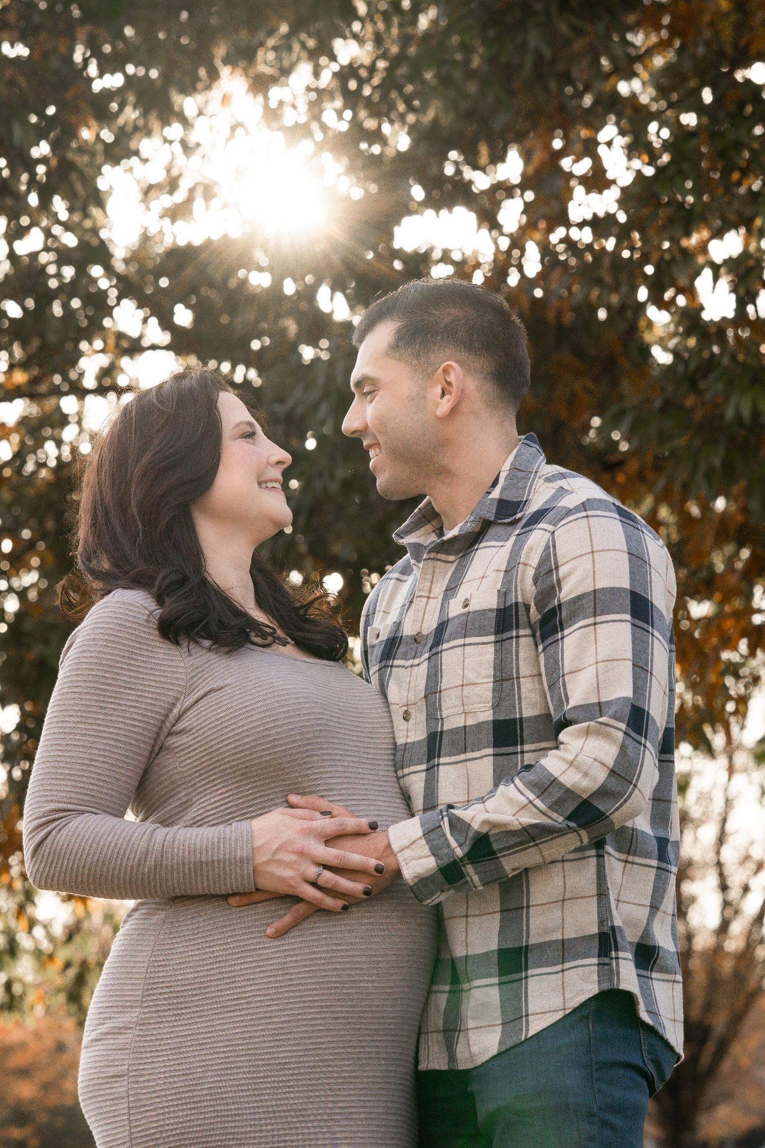 A couple shares a joyful moment together during a sunset photoshoot in an outdoor autumn setting.