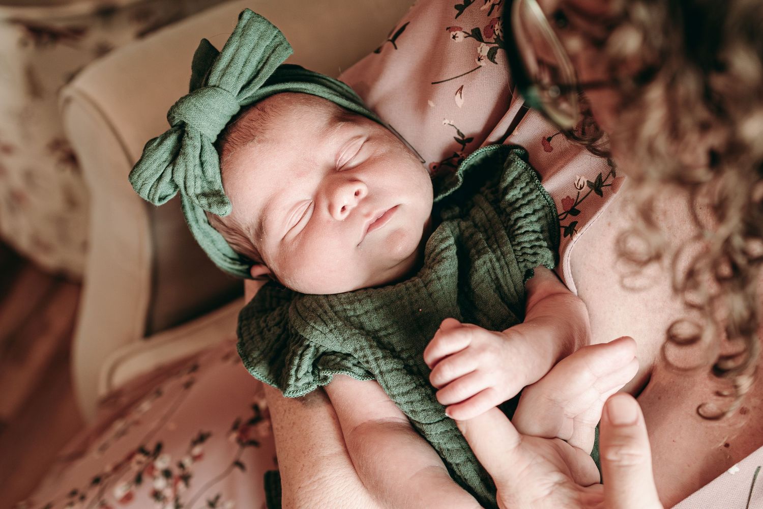 Sleeping newborn in vintage-style mint green bow headband and outfit laying on textured blanket.